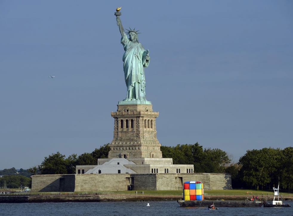 A tugboat tows a giant inflatable likeness of a Rubik's Cube puzzle near the Statue of Liberty on July 11, 2014  in New York to mark Hungarian architecture professor and inventor Erno Rubik turning 70 on July 13, the anniversary of his July 13, 1944, birt