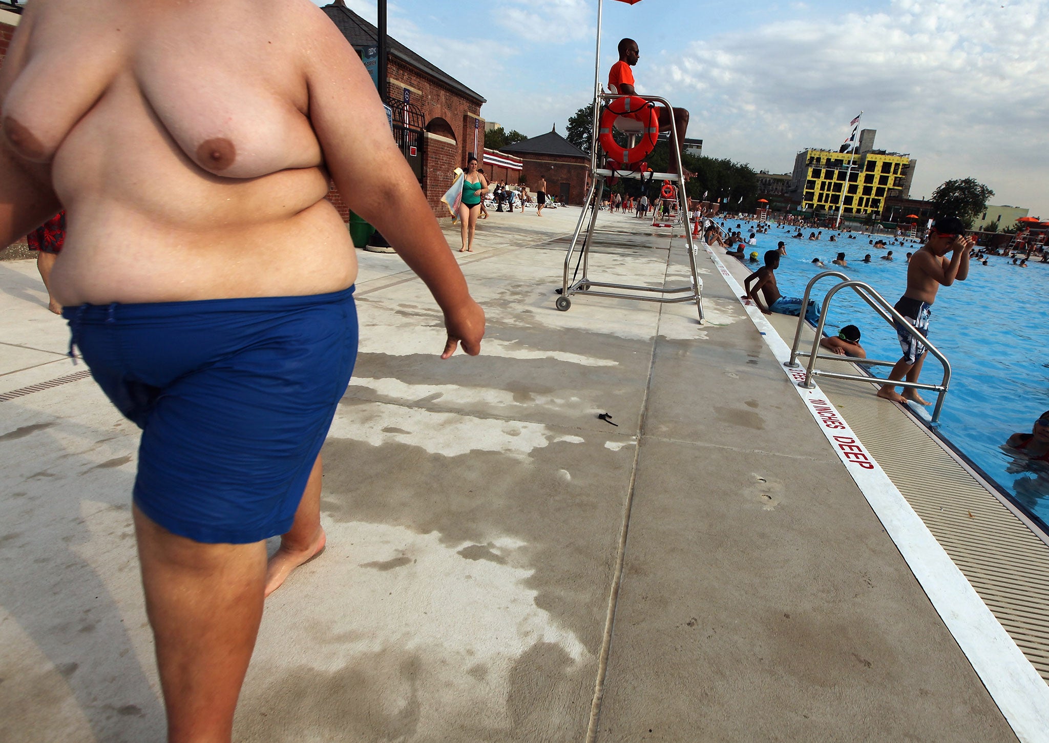 An obese man cools off by a pool