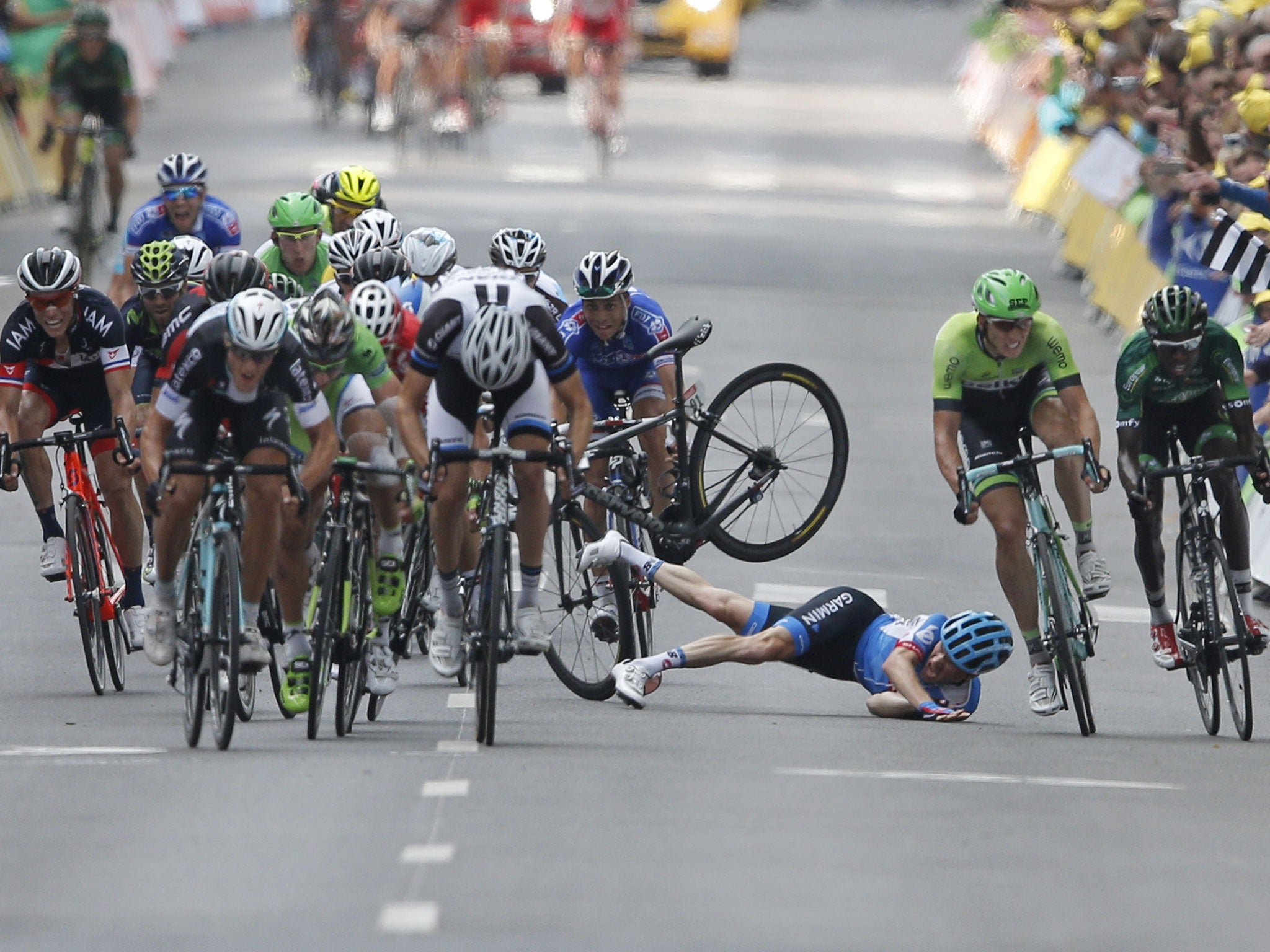 Andrew Talansky, of the US, crashes as the pack, with
stage winner, Matteo Trentin, (foreground left), sprints
towards the finish line