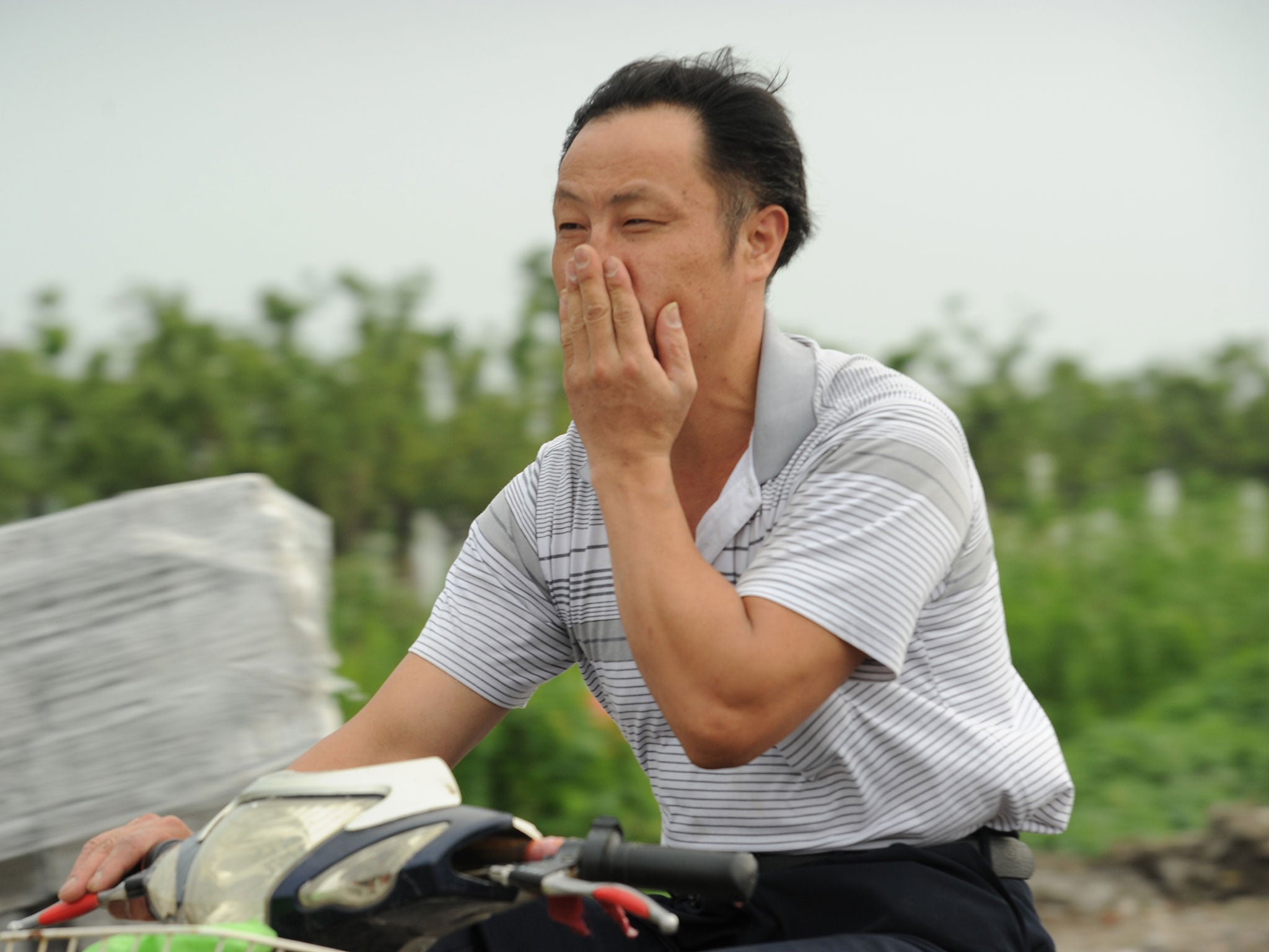 A man, unrelated to the study, on his motorcycle covers his nose against a bad smell