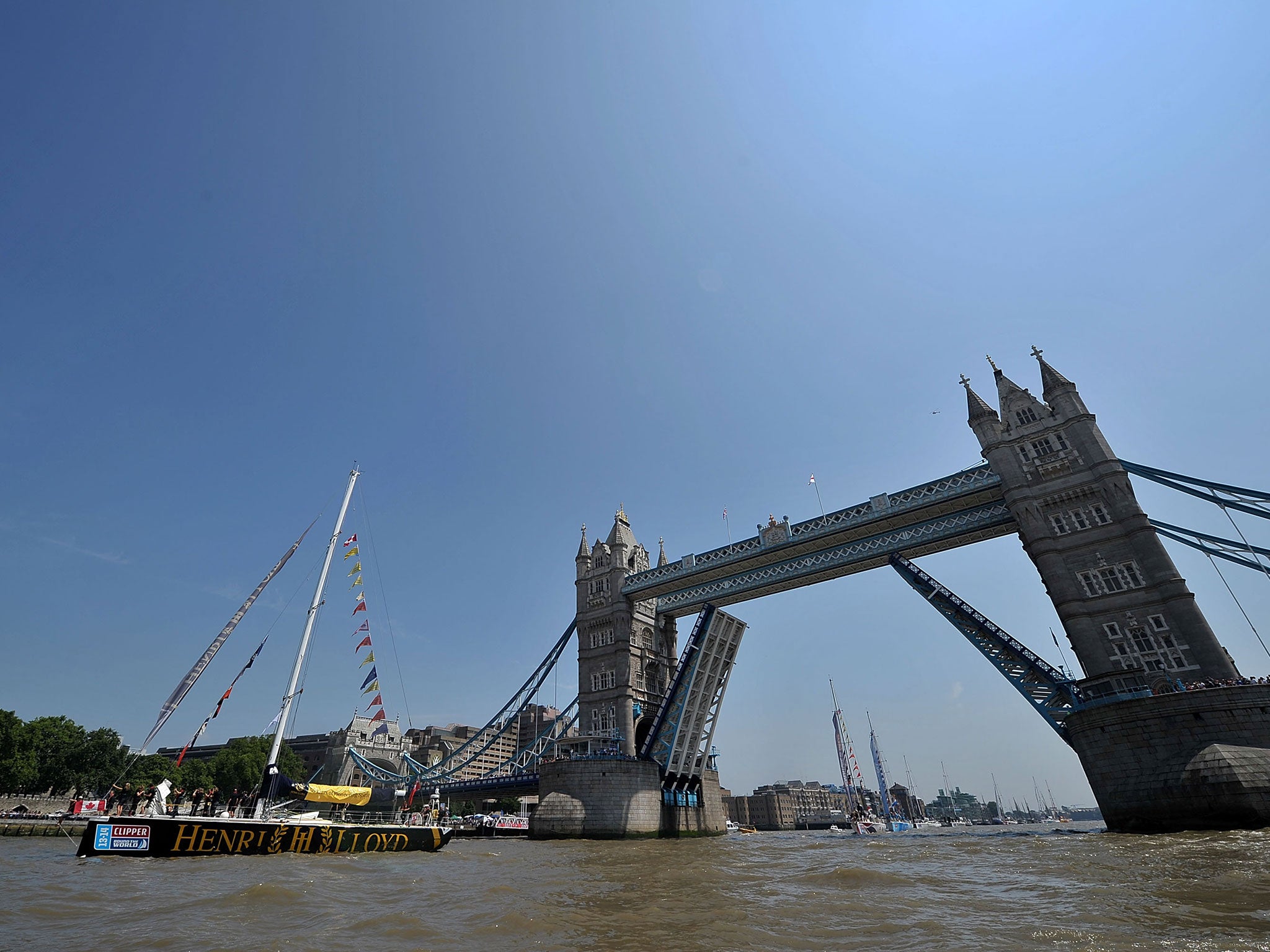 The winning Henri Lloyd Clipper Round the World yacht passes under Tower Bridge as part of a victory parade, mooring at St Katharine's dock on 12 July, 2014 in London, England