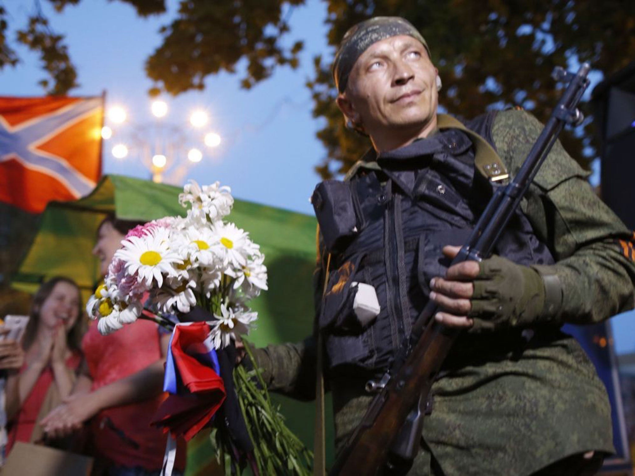 A pro-Russian rebel holds flowers, a gift from local residents, in Donetsk, where despite the smiles and laughter on show, tensions and violence escalated over the weekend