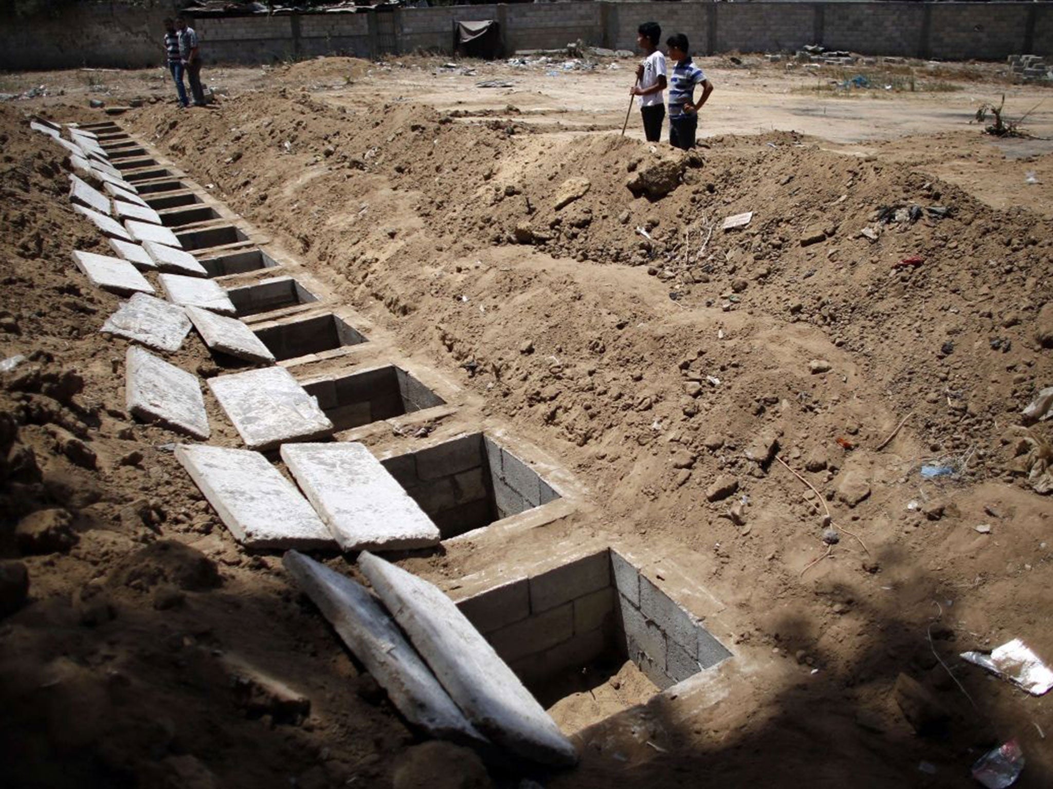 Two children stand by a line of graves