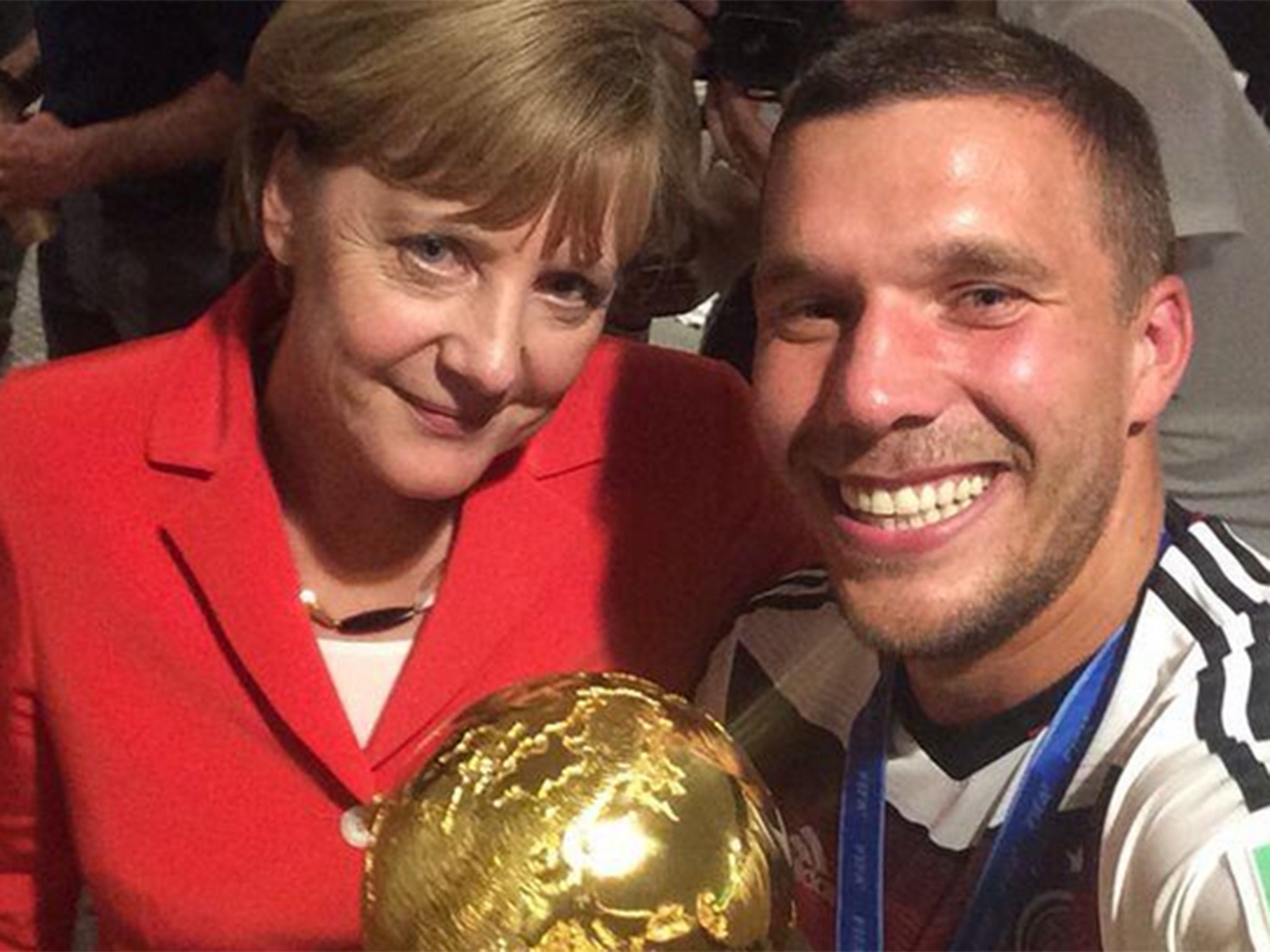 Lukas Podolski poses with German Chancellor Angela Merkel
