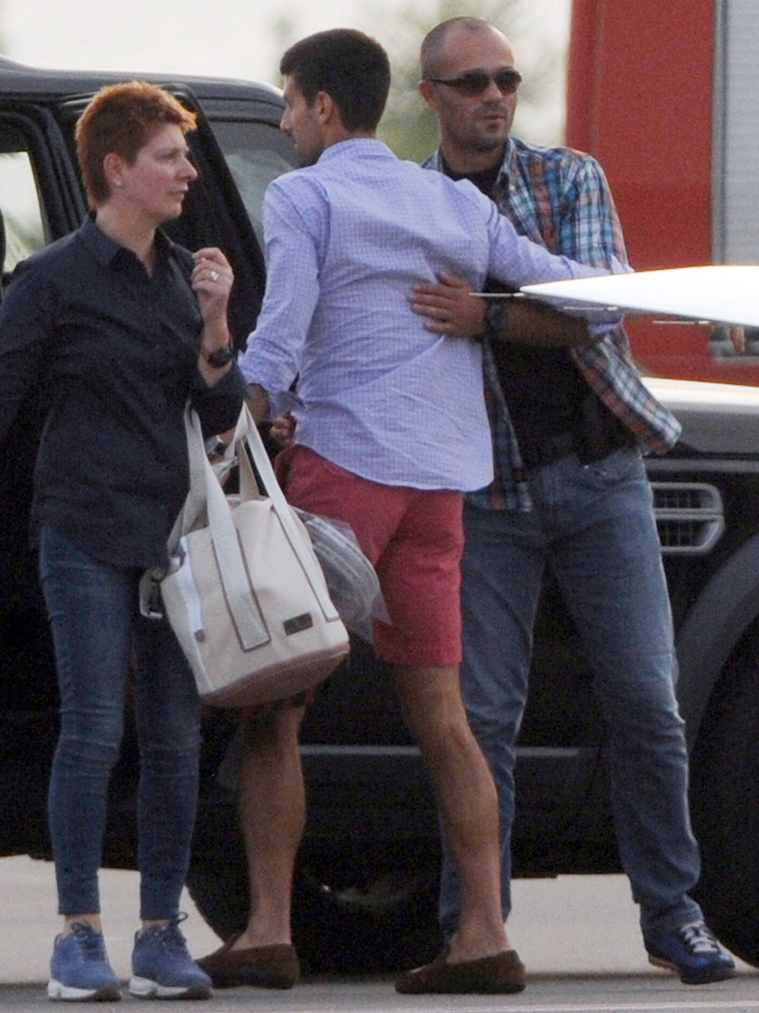 Novak Djokovic, greeted by his security officer, enters a vehicle after landing at Tivat airport