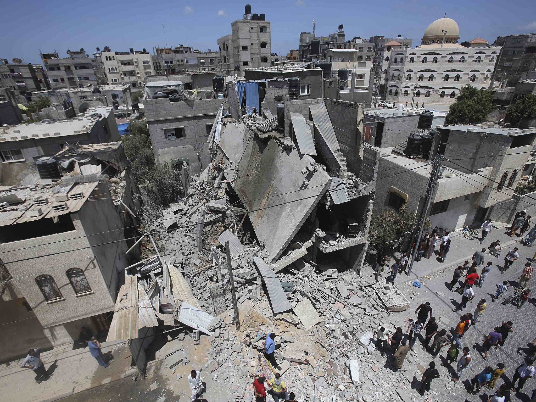 Palestinians gather around the remains of a house, which police said was destroyed in an Israeli air strike in Rafah