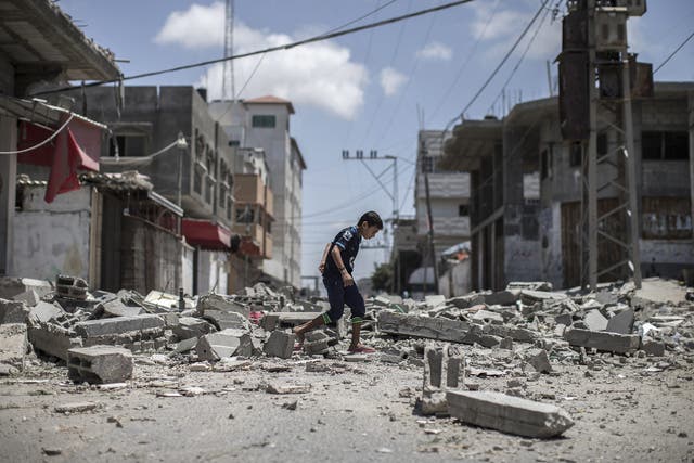 A young Palestinian boy walks over debris from a house that was destroyed in an airstrike in Deir Al Balah 