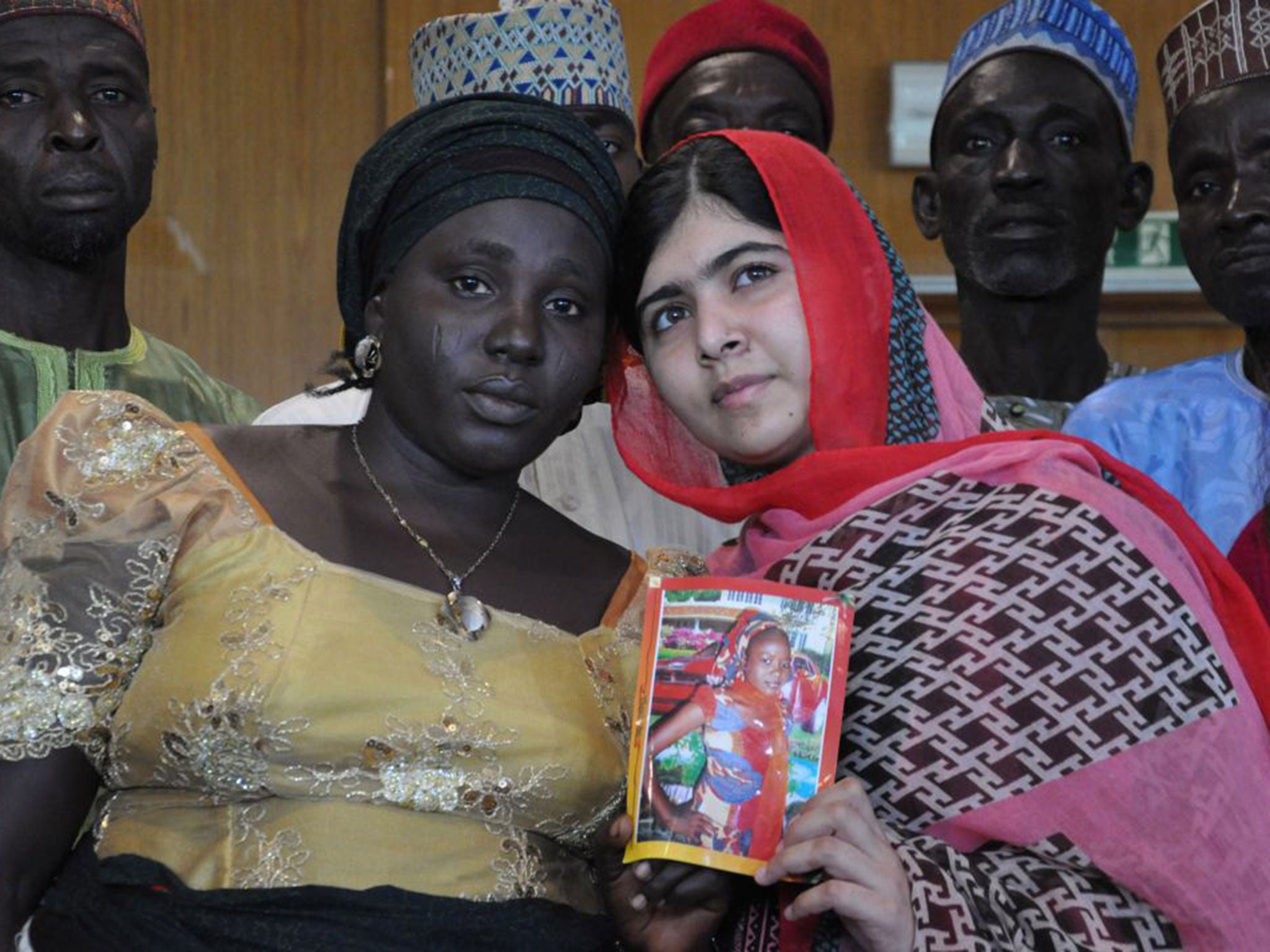 Malala holds a picture of a kidnapped girl, with her mother