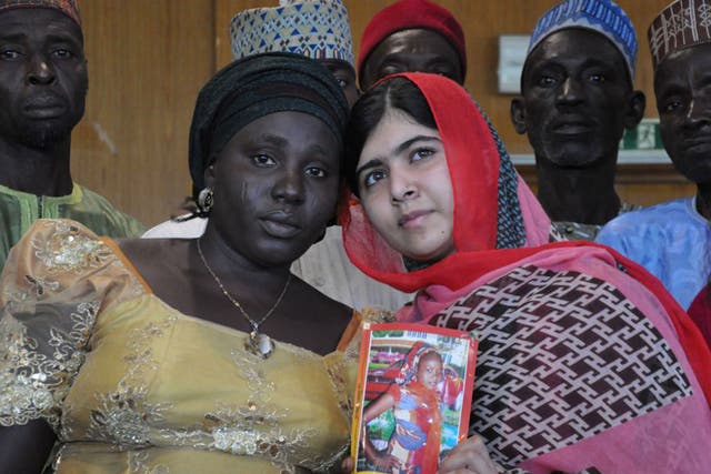 Malala holds a picture of a kidnapped girl, with her mother 