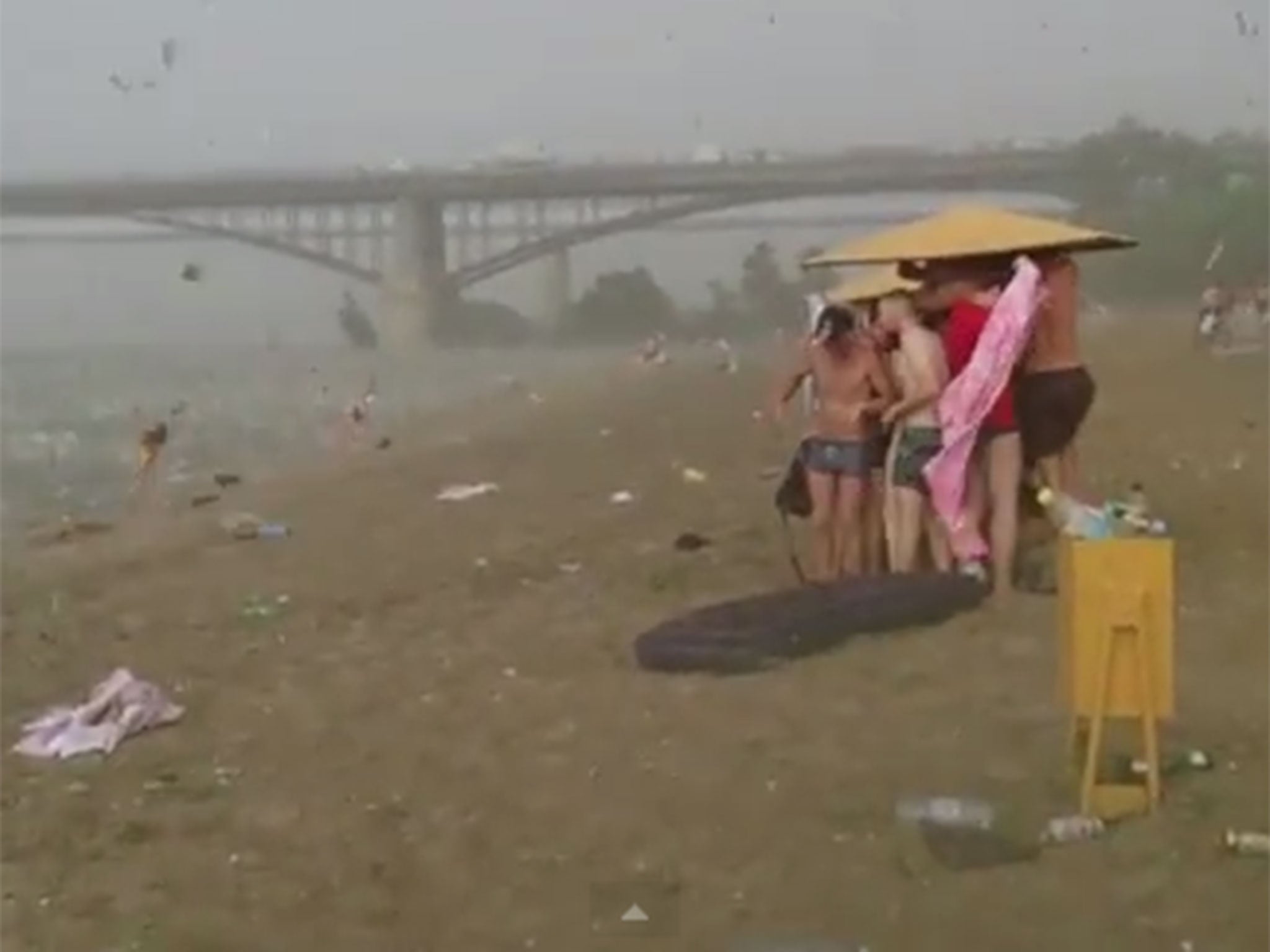Beach-goers seek cover under an umbrella