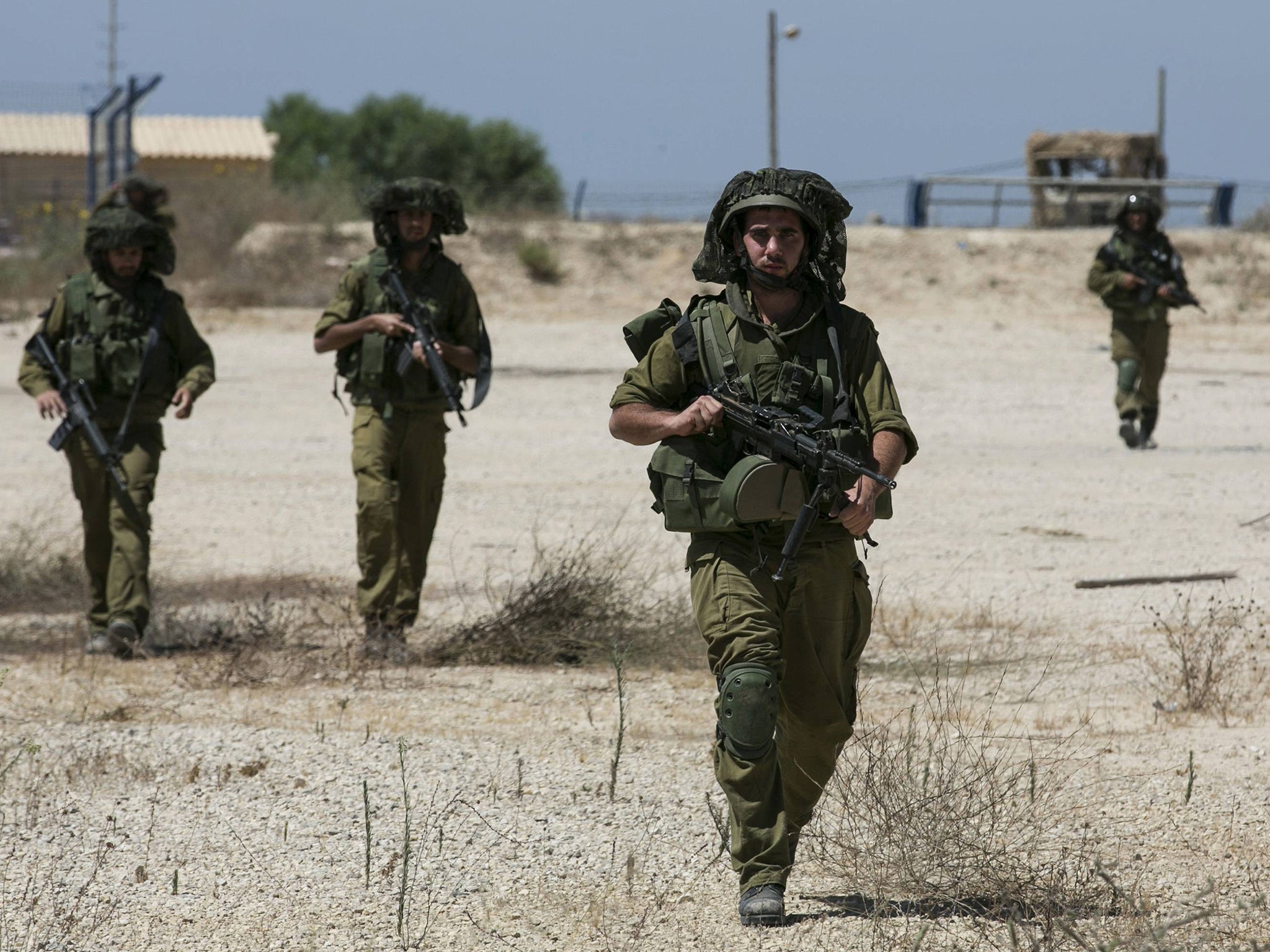 Israeli soldiers walk near the border with the central Gaza Strip