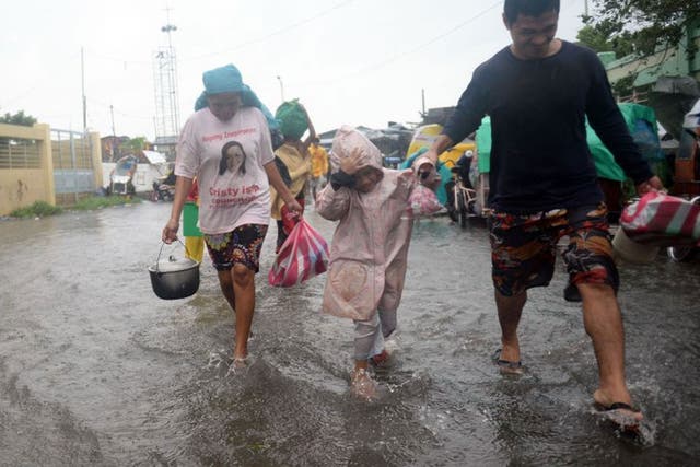 Residents cross a flooded street to an evacuation center as Typhoon Rammasun/Glenda barrels across Manila