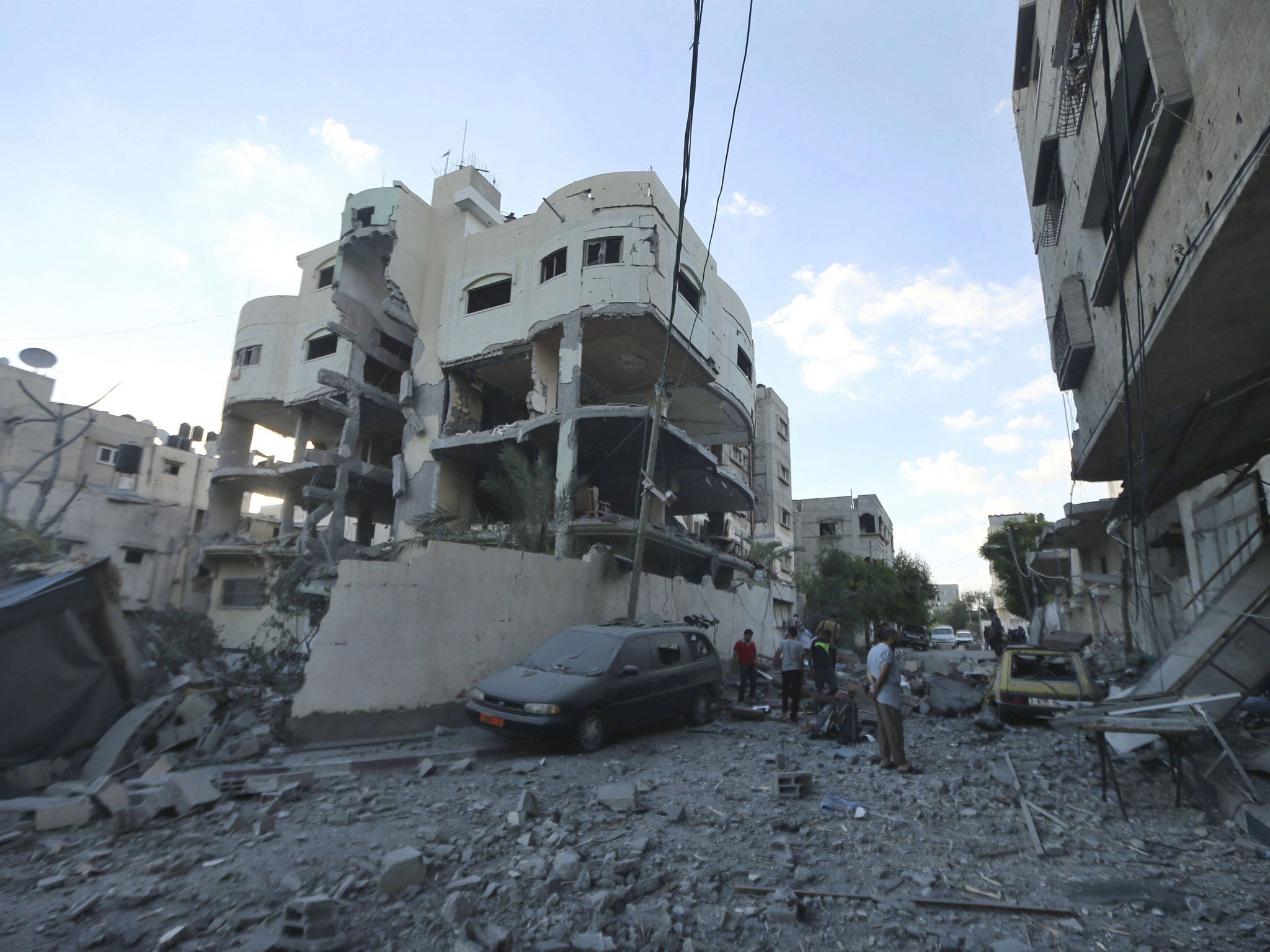 Palestinians stand next to the house (C) of top Hamas political leader Mahmoud Zahar, which police said was targeted by an Israeli air strike in Gaza on 16 July, 2014