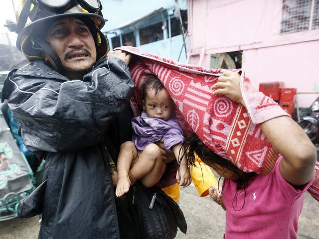 A Filipino rescue worker carries a child after an evacuation was implemented due to Typhoon Rammasun in Manila 