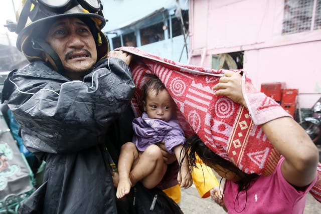 A Filipino rescue worker carries a child after an evacuation was implemented due to Typhoon Rammasun in Manila 