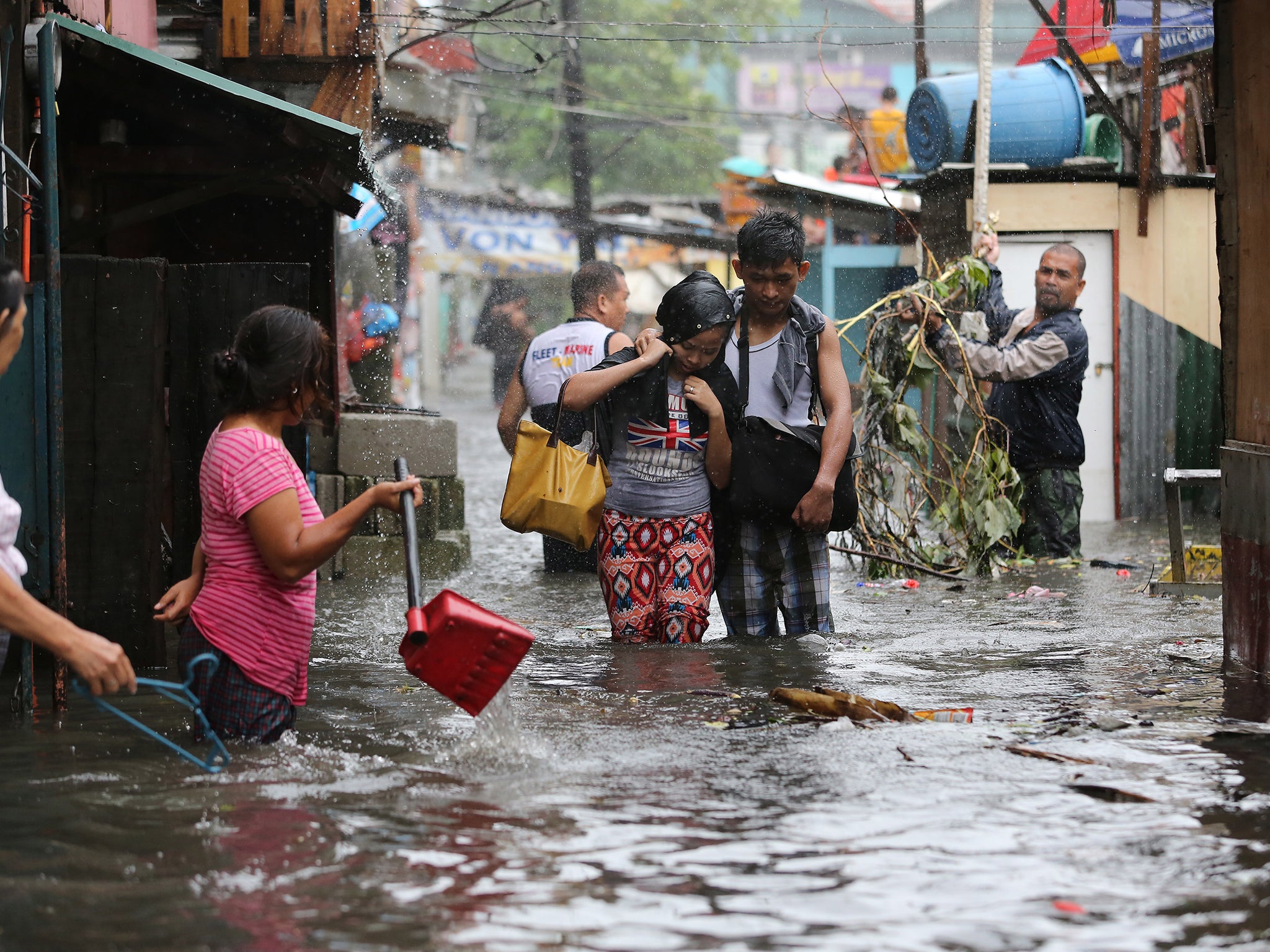 Residents wade through floods as they go back to their home while Typhoon Rammasun batters suburban Quezon city, north of Manila