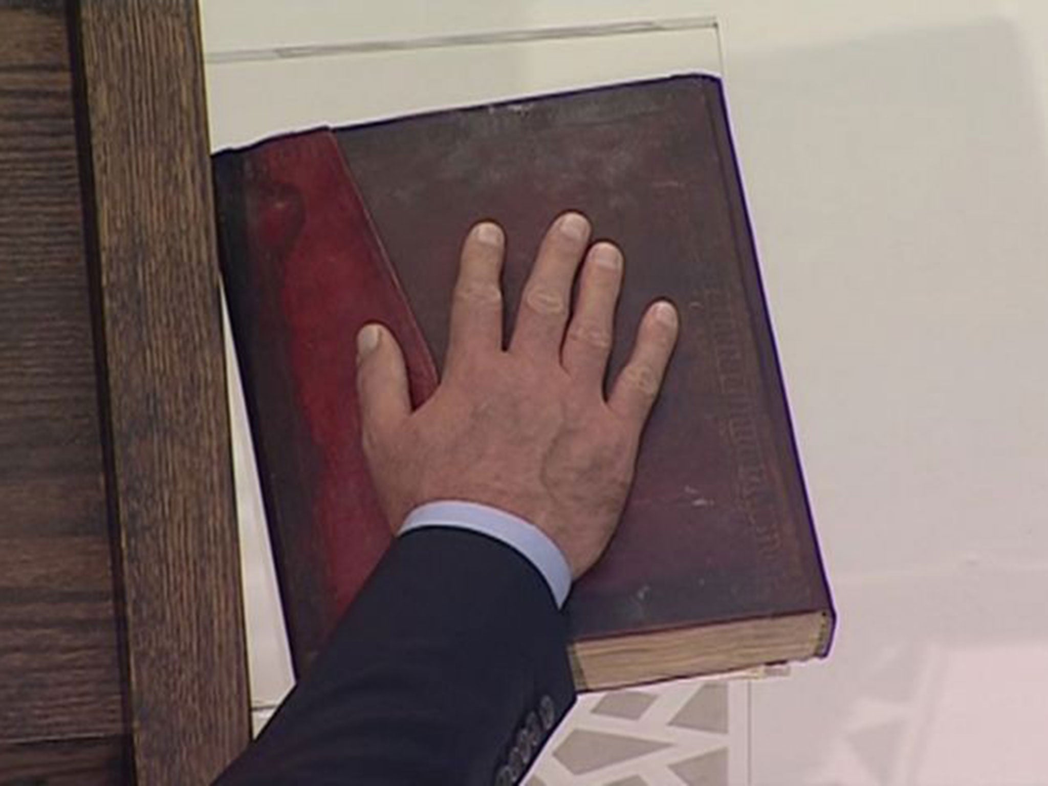 Assad places his hand on the Qur'an during the swearing-in (REUTERS)