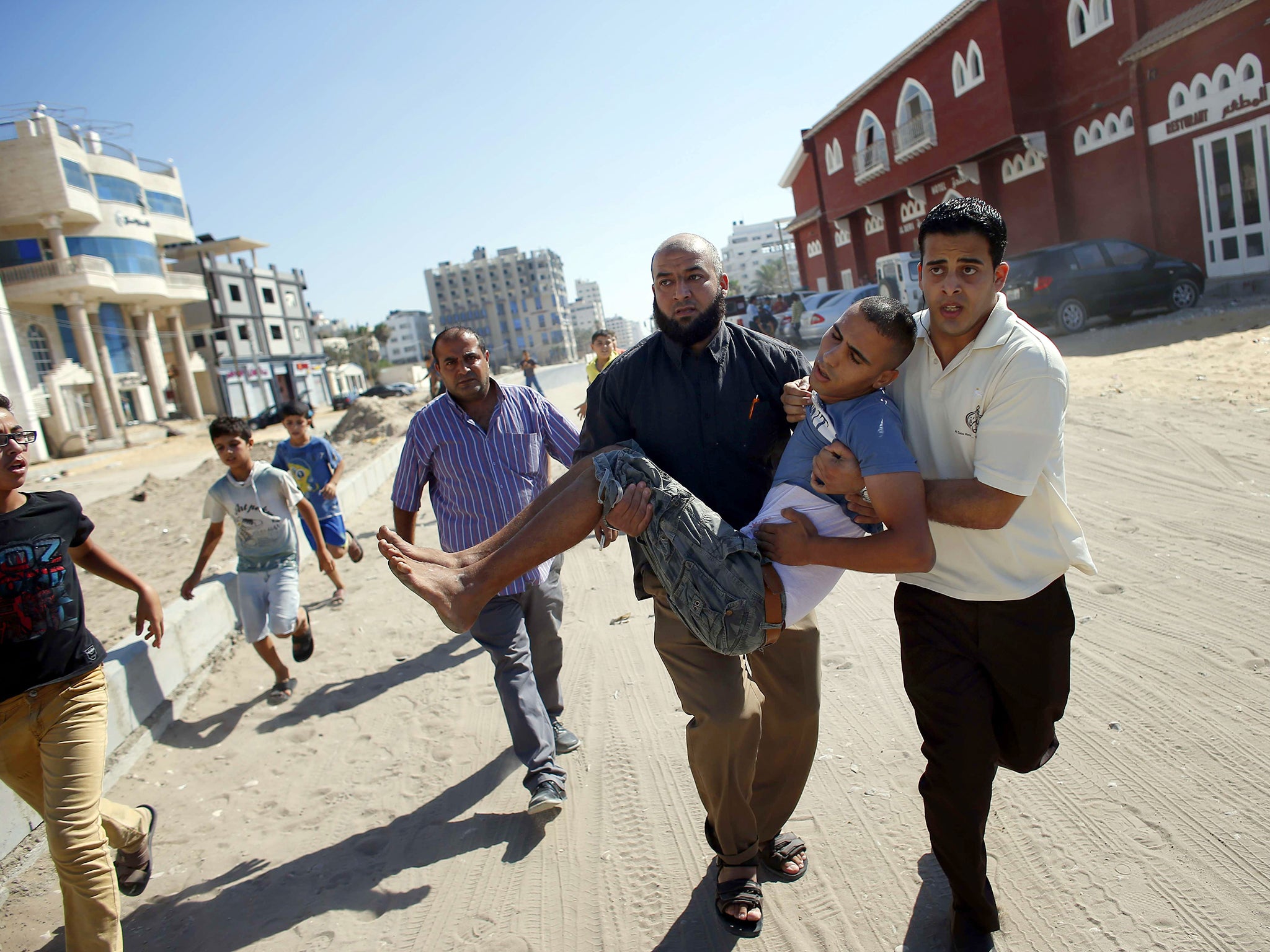 Palestinian employees of Gaza City's al-Deira hotel carry a wounded boy following an Israeli military strike nearby on the beach 