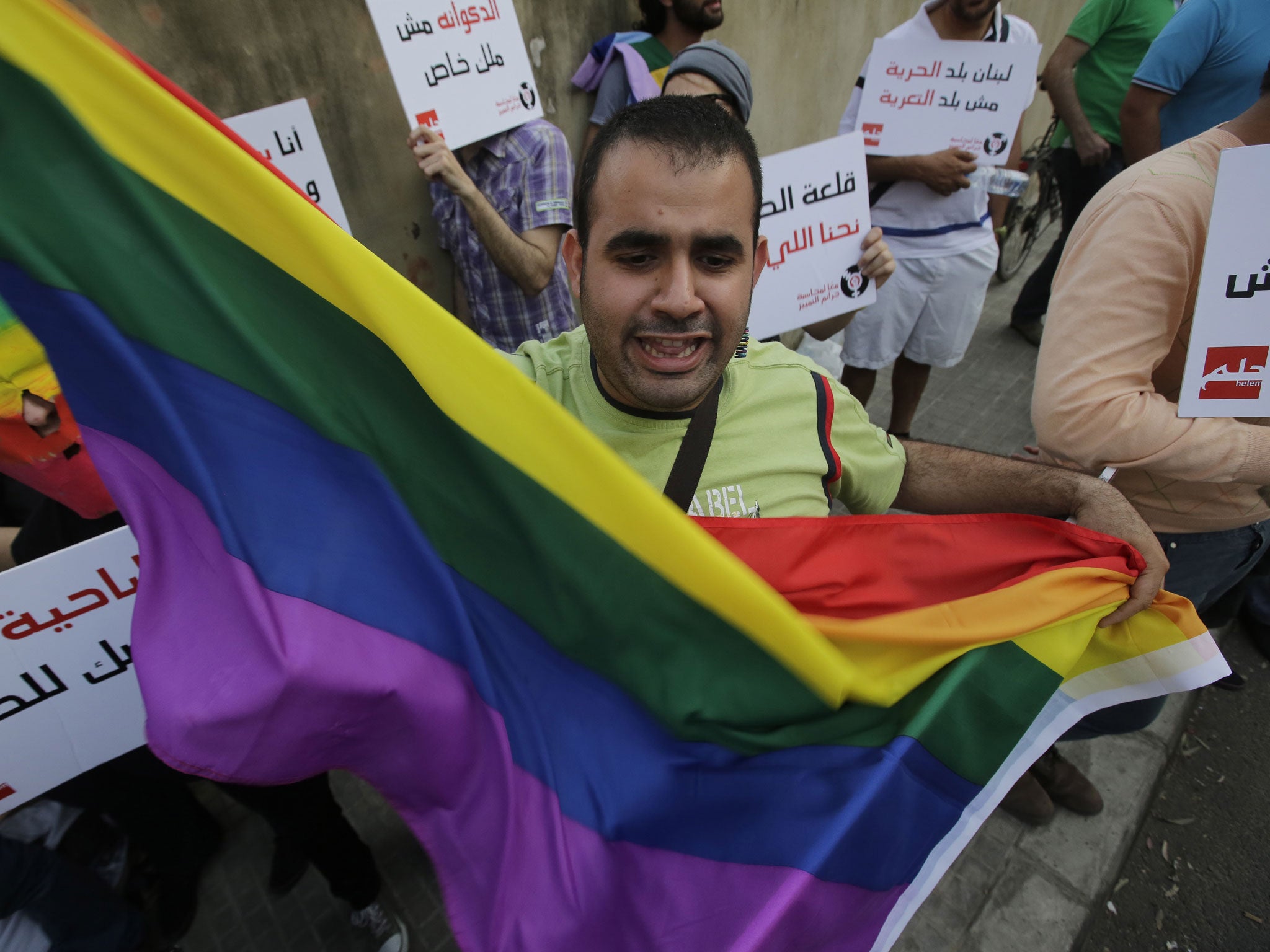 A protester waves a gay pride flag as others hold banners during an anti-homophobia rally in Beirut on April 30, 2013