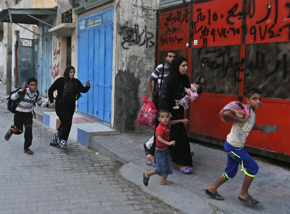 Palestinians run for shelter as they hear bombing in the distance while they flee their homes in the Shajaiyeh neighborhood of Gaza City, after Israel had airdropped leaflets warning people to leave the area 