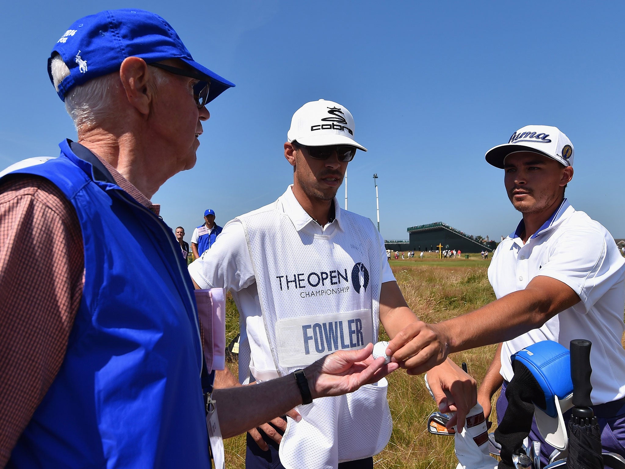 Marshal Bill Davis receives a golf ball from Rickie Fowler