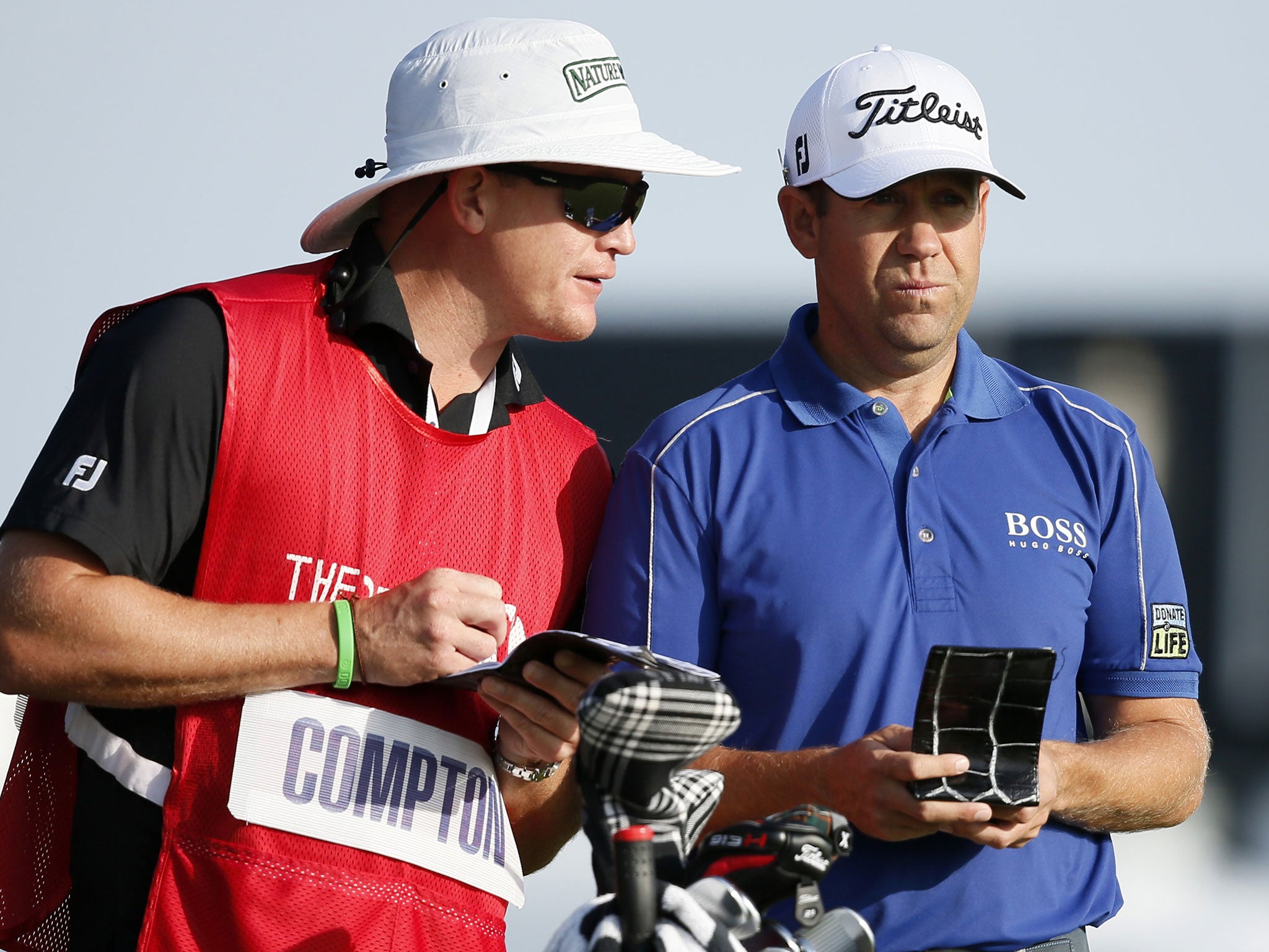 Erik Compton consults his caddie over a shot in his first round