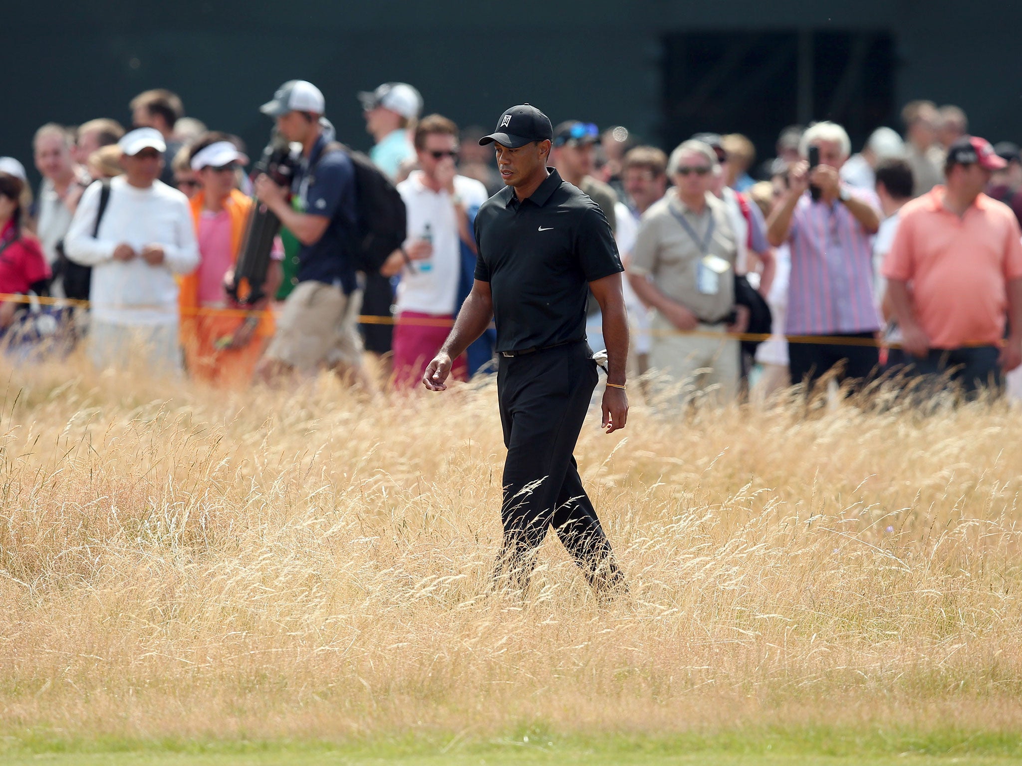 Tiger Woods goes searching for his ball in the rough after a stray drive on the first hole of the day