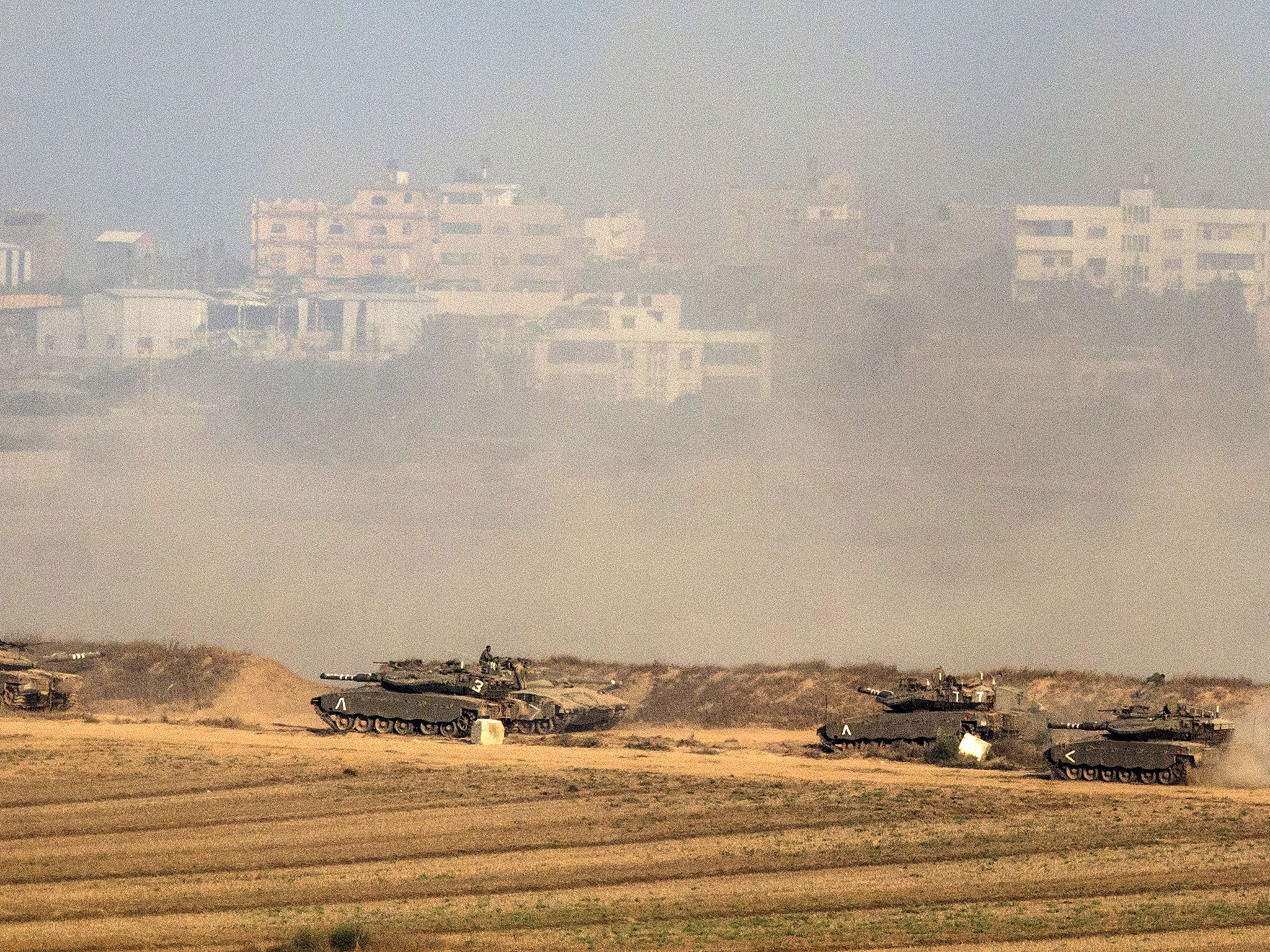 Israeli Merkava tanks fire at the Gaza Strip (background) from their position near Israel's border with the Strip on July 20, 2014