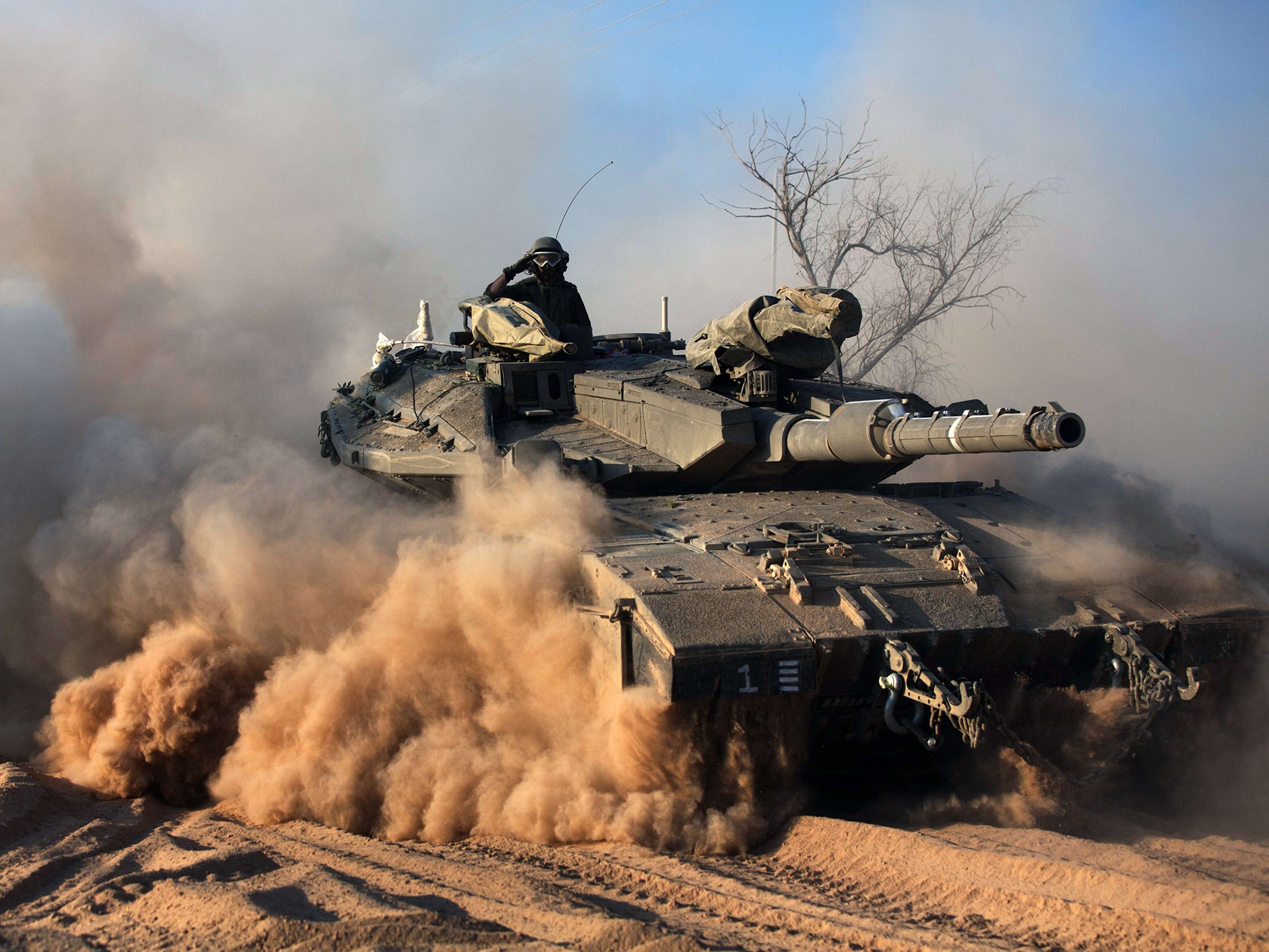 An Israeli soldier gestures on a Merkava tank, as part of the Israeli army deployment near Israel's border with the Gaza Strip