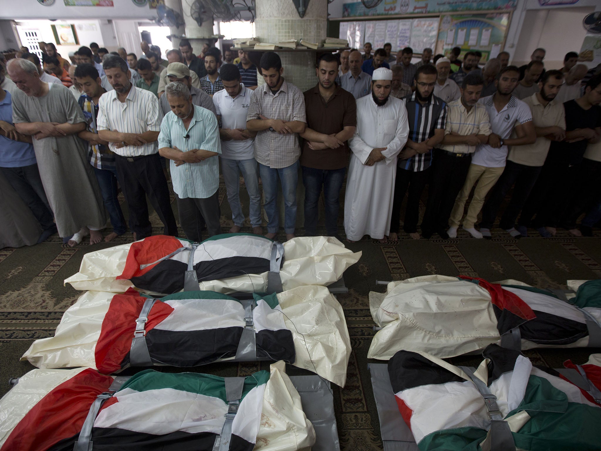 Palestinian mourners pray over five bodies, all from the Halaq family, during their funeral in the Jabalia refugee camp, in the Gaza Strip, on 21 July 2014