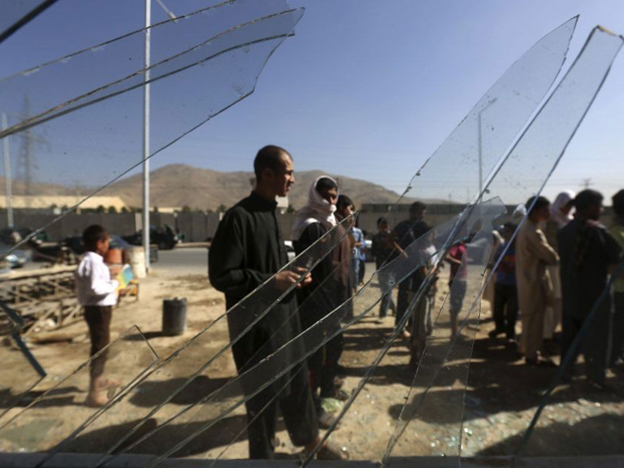 Afghans are seen through broken glass at a shop at the site of the blast