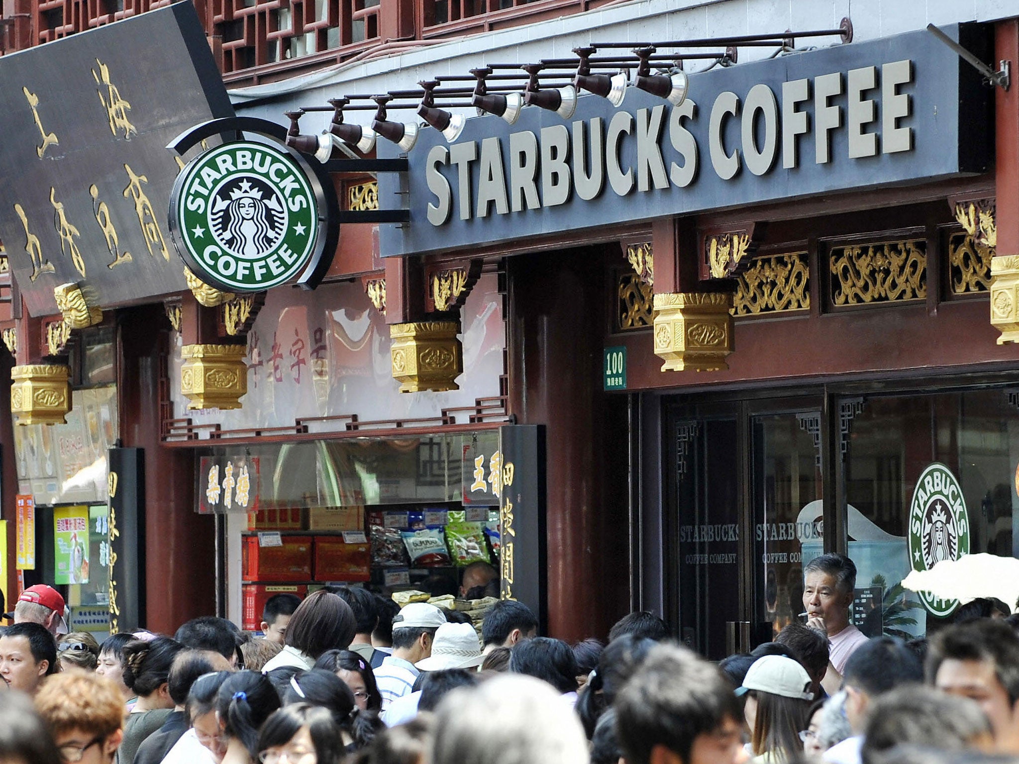 Pedestrians make their way past a Starbucks coffee shop in a street in the Chinese city Shanghai's old town