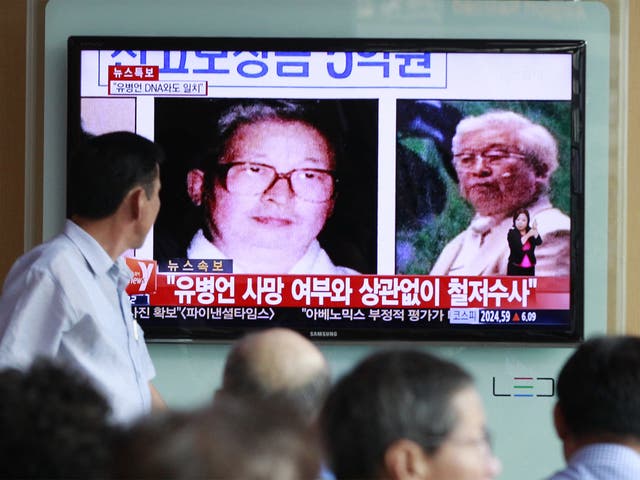 People watch a TV news showing portraits of Yoo Byung-eun, the fugitive owner of the sunken ferry Sewol, at Seoul Railway Station