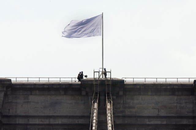 New York City Police officers stand at the base of a white flag flying atop the west tower of New York's Brooklyn Bridge, Tuesday, July 22, 2014. Someone replaced two American flags on the bridge with mysterious white flags. The white flags, international