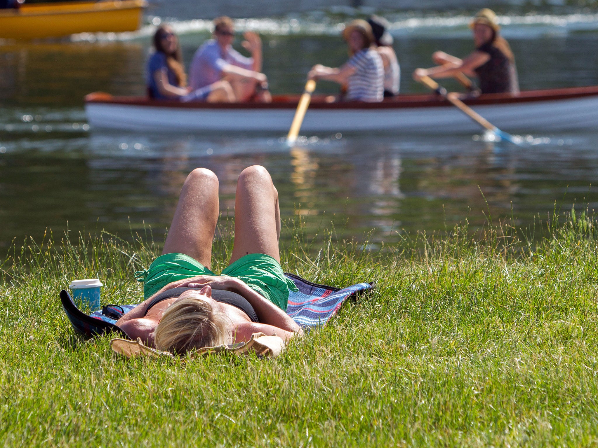 People sunbath on the bank of the river Thames in Windsor