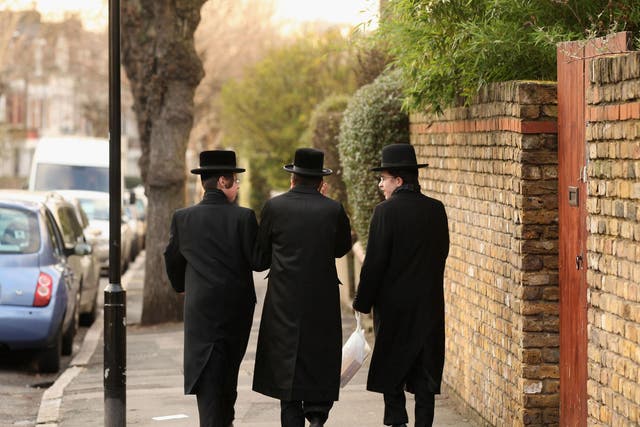 Jewish men walk along the street in the Stamford Hill area of north London