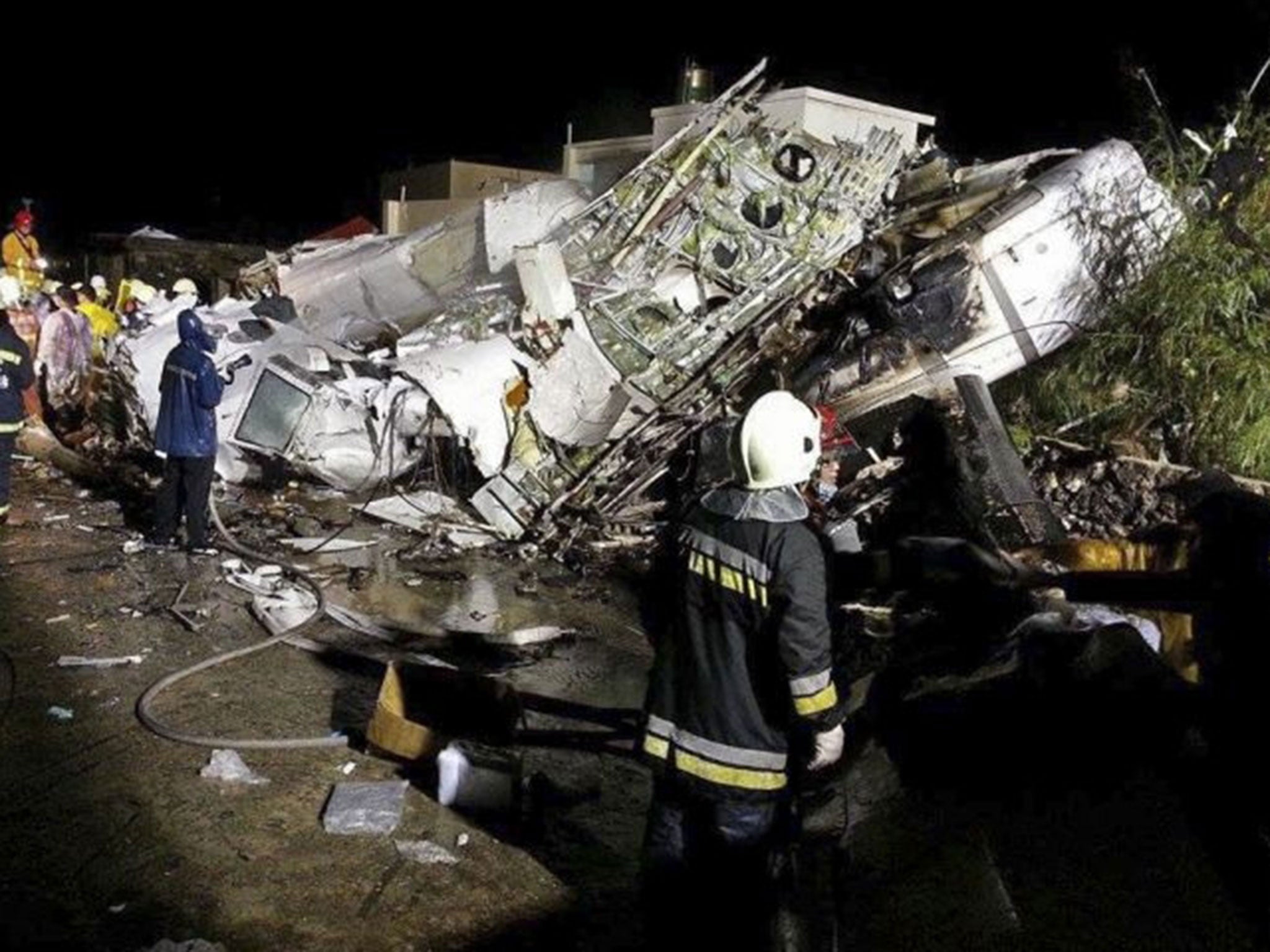 Rescue workers survey the wreckage of TransAsia Airways flight GE222 which crashed while attempting to land in stormy weather on the Taiwanese island of Penghu, late Wednesday, July 23, 2014. A transport minister said dozens of people were trapped and fea