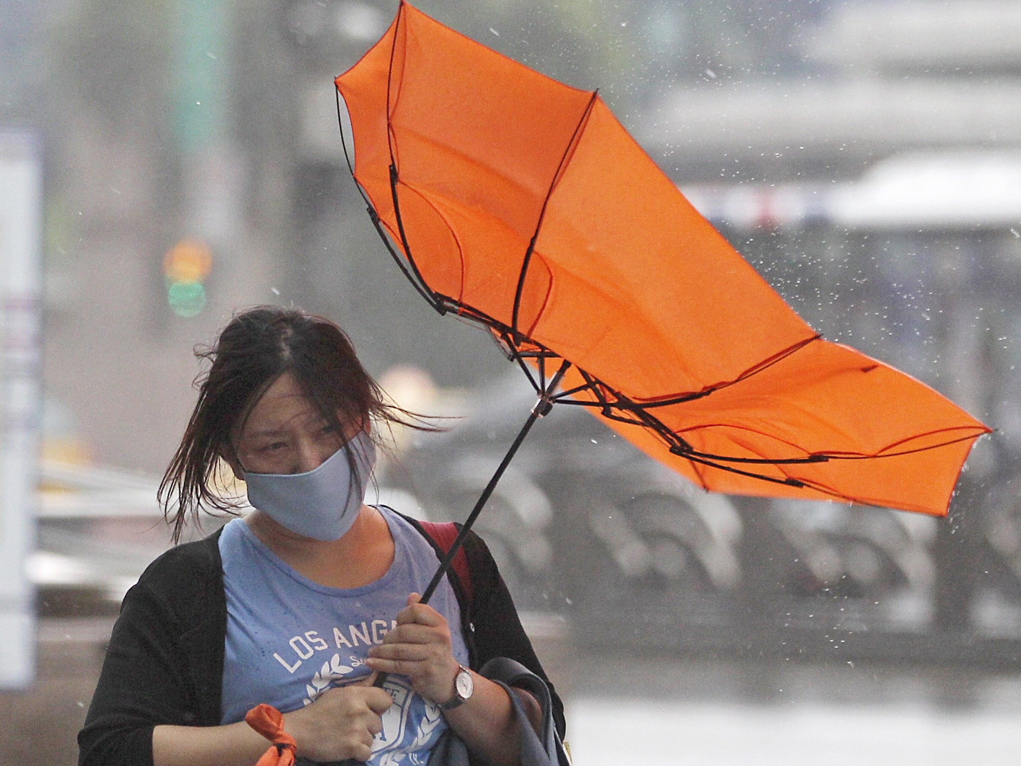 A woman holds her umbrella while walking against strong winds as Typhoon Matmo hits Taiwan