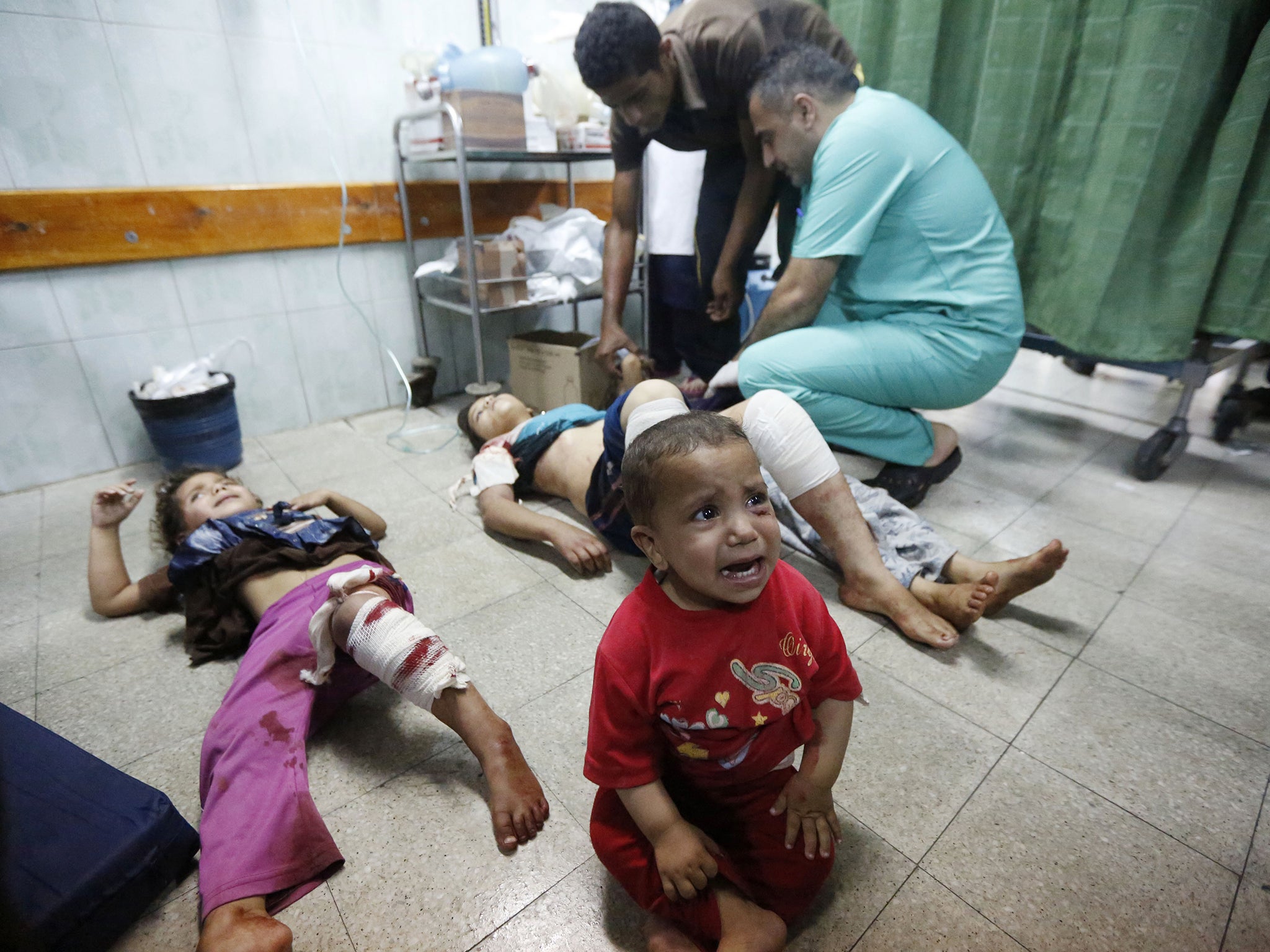 Palestinian children, wounded in an Israeli strike on a compound housing a U.N. school in Beit Hanoun, in the northern Gaza Strip, cry as they lay on the floor at the emergency room of the Kamal Adwan hospital in Beit Lahiya