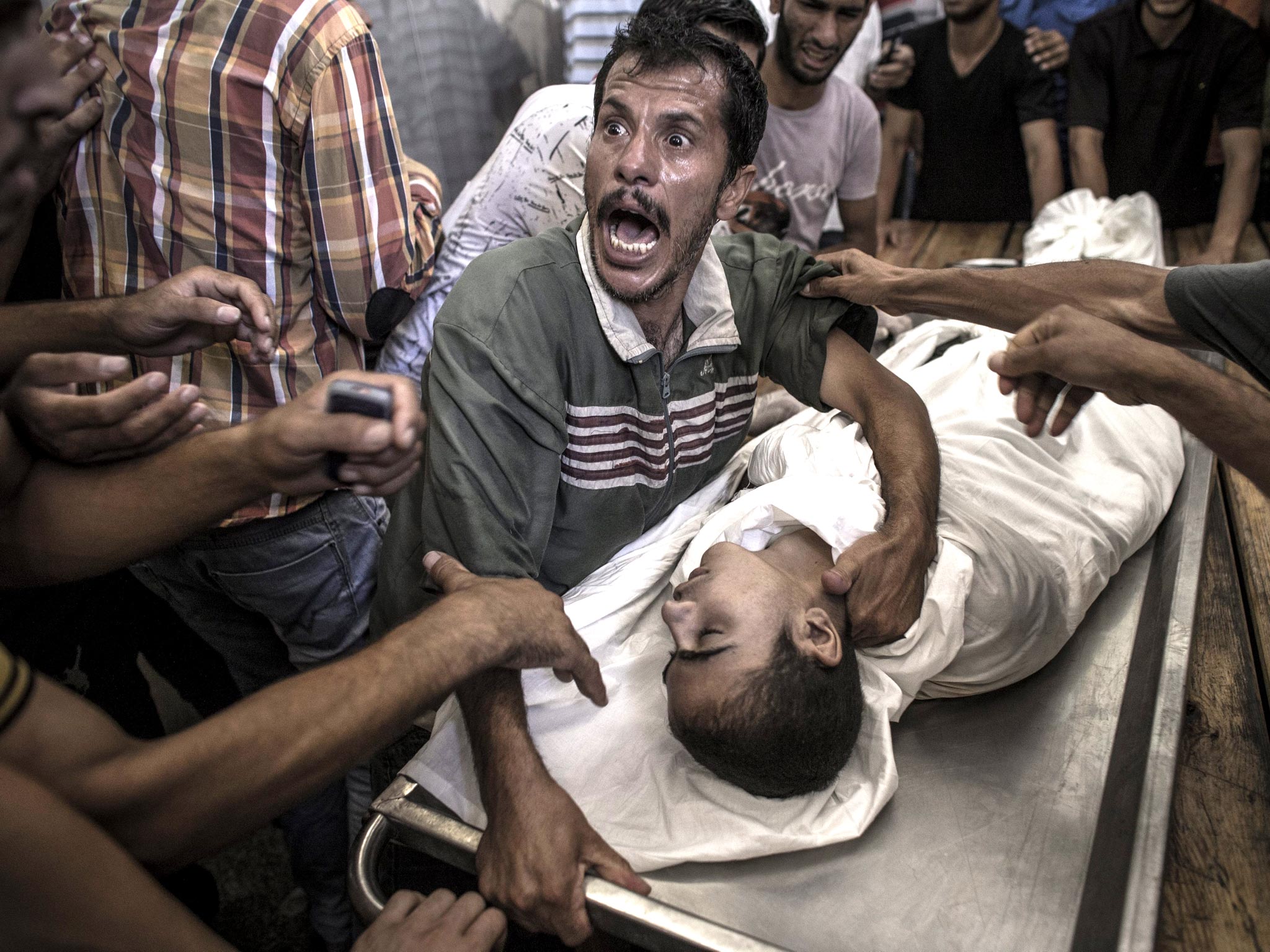 A father cries over the body of his son who died when the UN school for refugees in Beit Hanoun was attacked