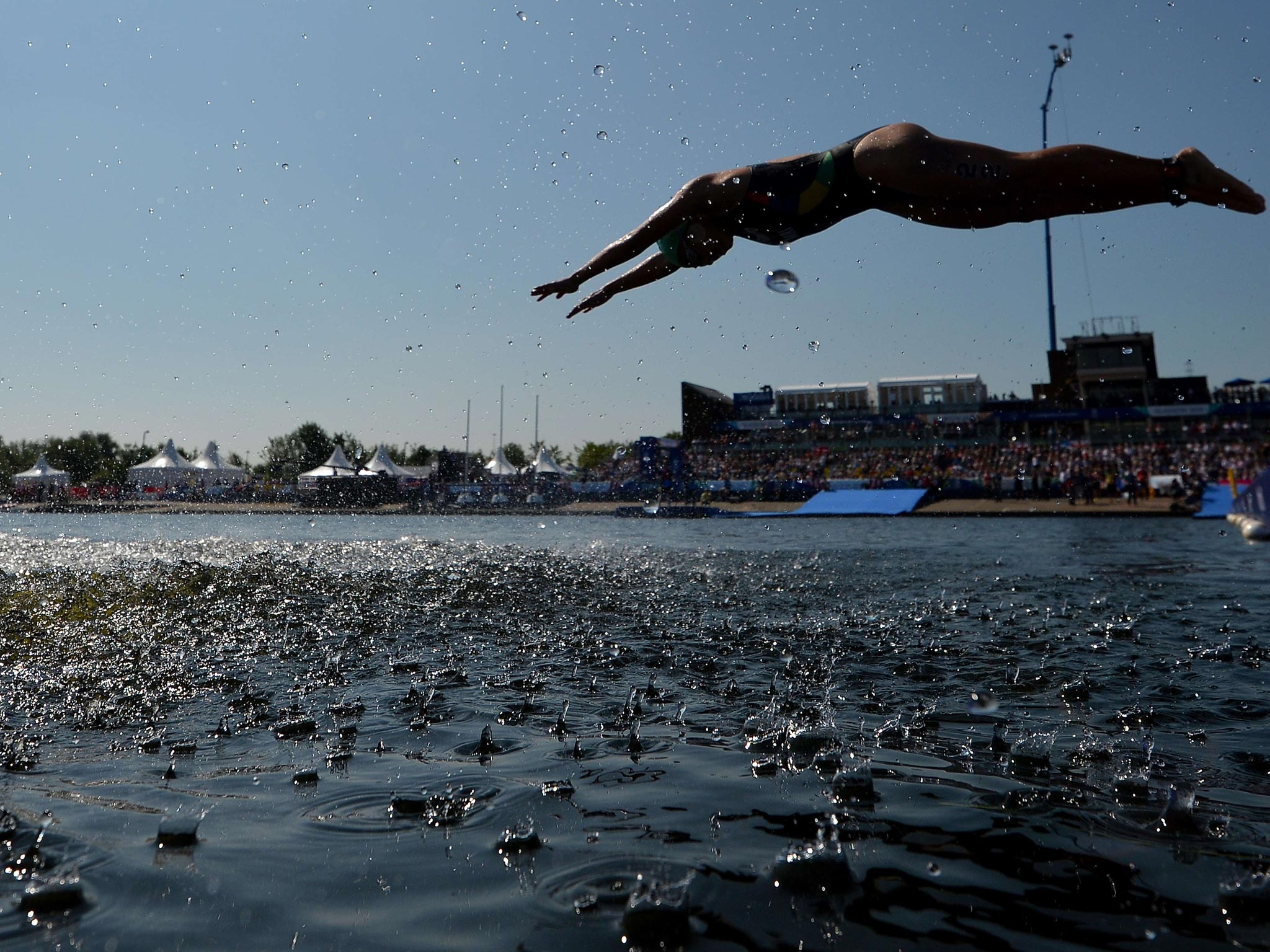 An athlete dives into the water after the first lap of the swim phase during the Women's Triathlon during the 2014 Commonwealth Games