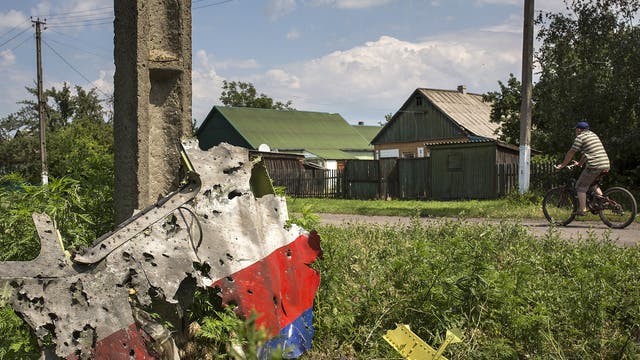 A man cycles past a piece of the wreckage of the Malaysia Airlines flight MH17 in Petropavlivka, Ukraine 