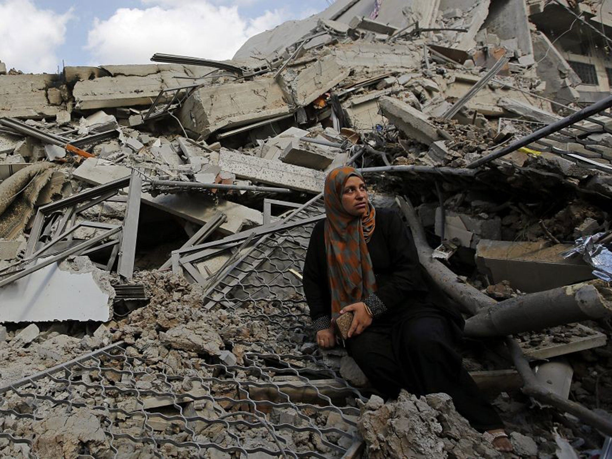 A Palestinian woman sits at the ruble of her destroyed house in Shuja'iyya neighbourhood in eastern Gaza City