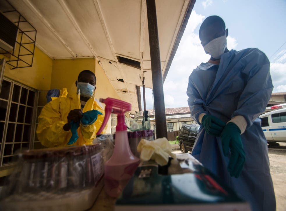 Health workers put on protective gear while working with suspected Ebola patients in Kenema, Sierra Leone