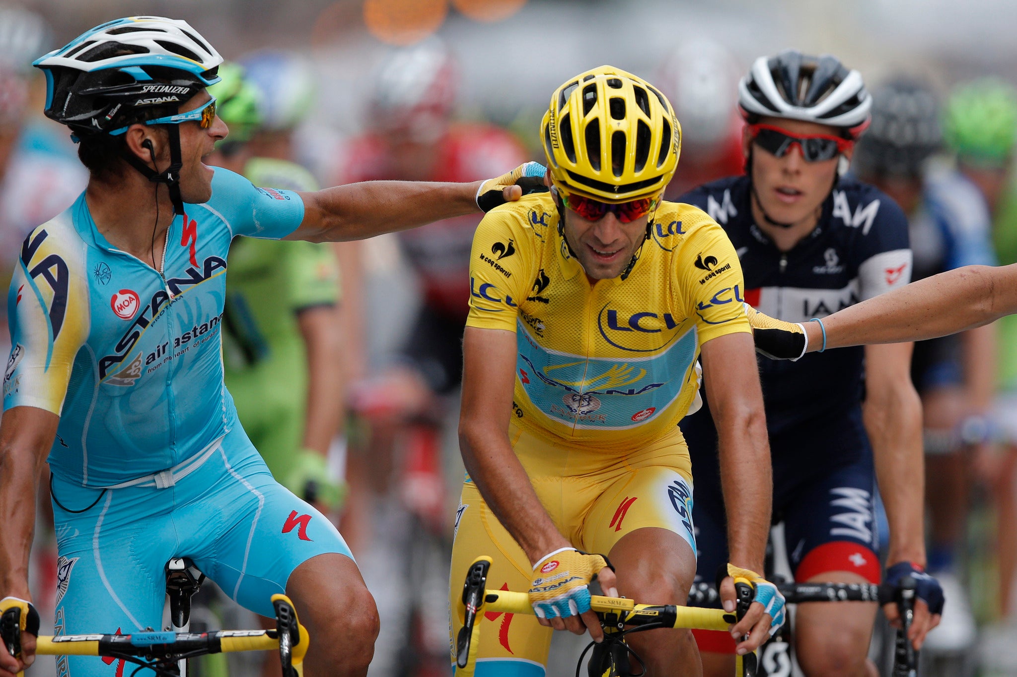 Italy's Vincenzo Nibali, wearing the overall leader's yellow jersey, is congratulated by teammates as he crosses the finish line of the final stage of the Tour de France