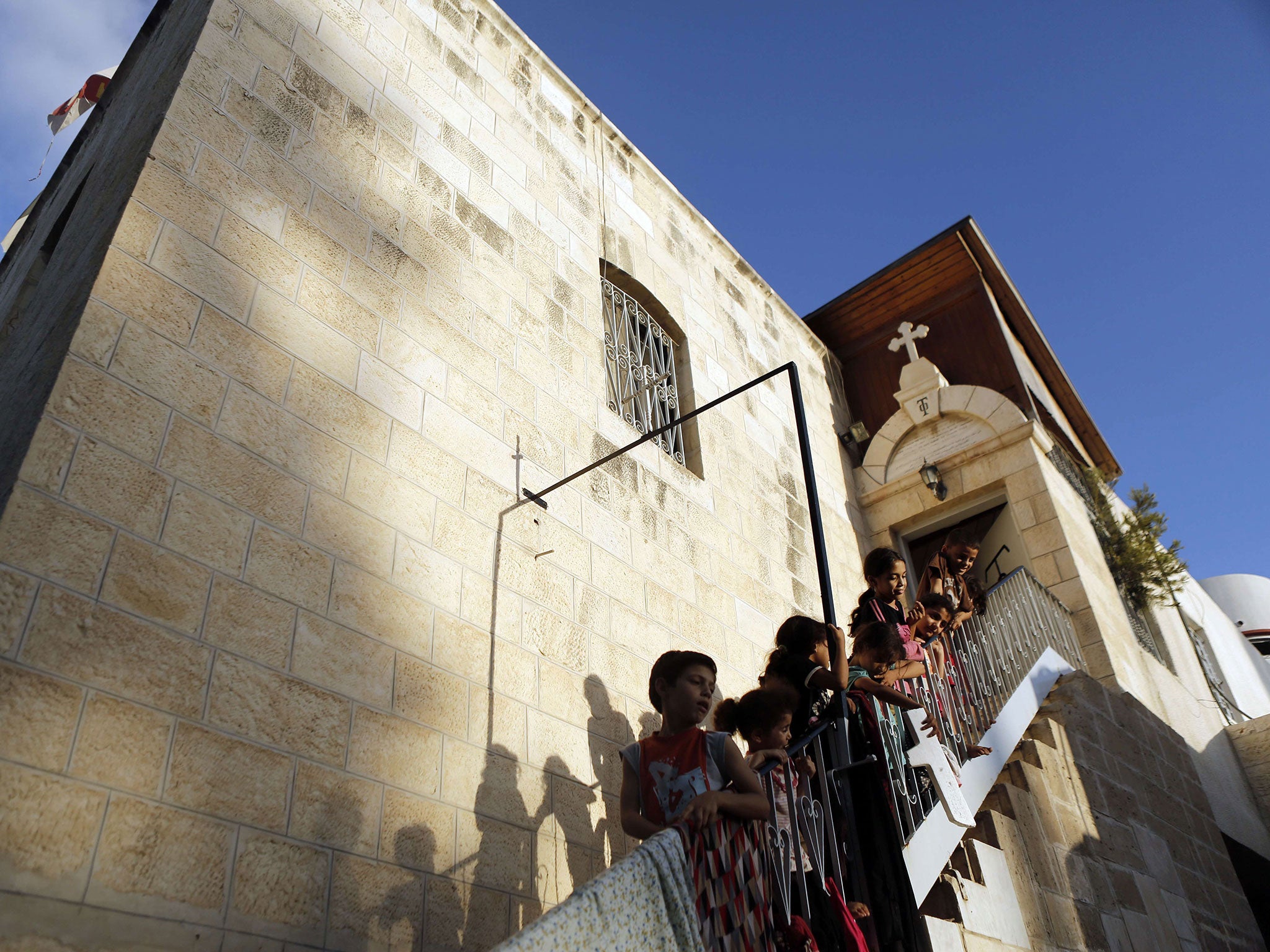 Displaced Palestinian children stand on the stairs of St Porphyrios Greek Orthodox church in Gaza City