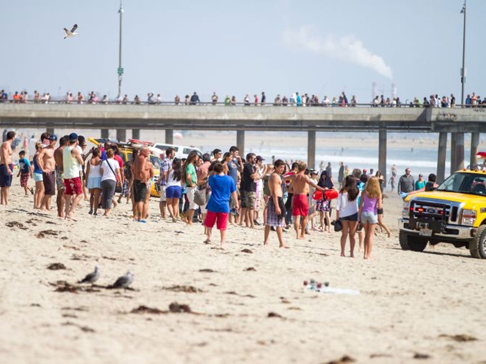 Pedestrians and beachgoers stand on the shore near Venice Beach as lifeguards, right, bring in a swimmer rescued from the water after a lightning strike Sunday July 27,