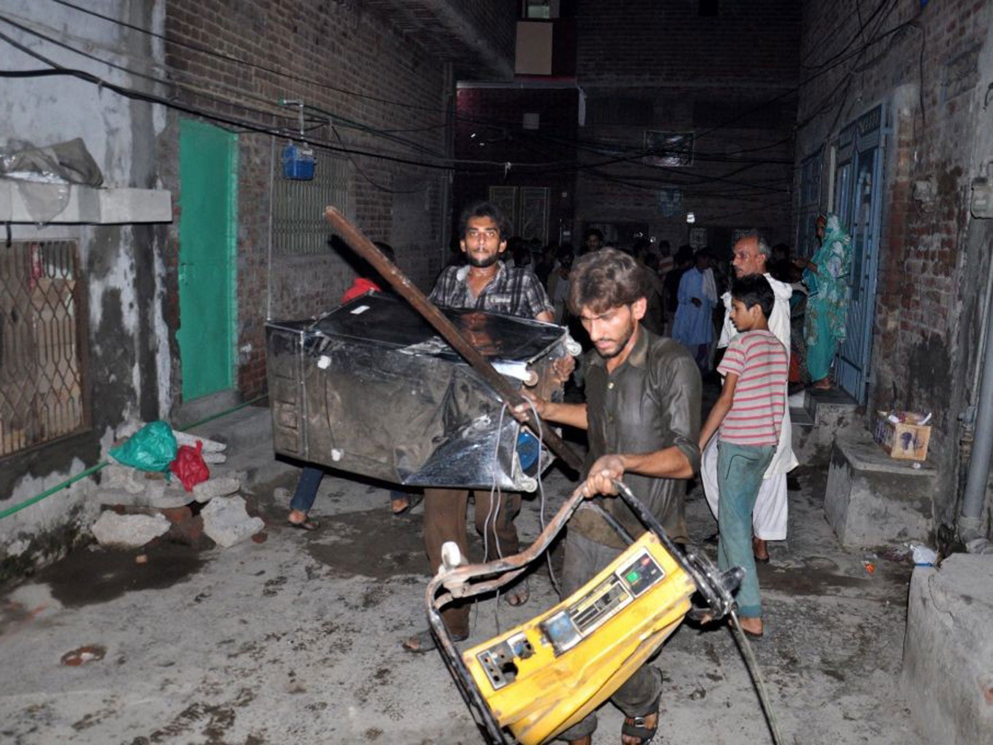 A mob collects the belongings of Ahmadis following accusations of blasphemy, in Gujranwala