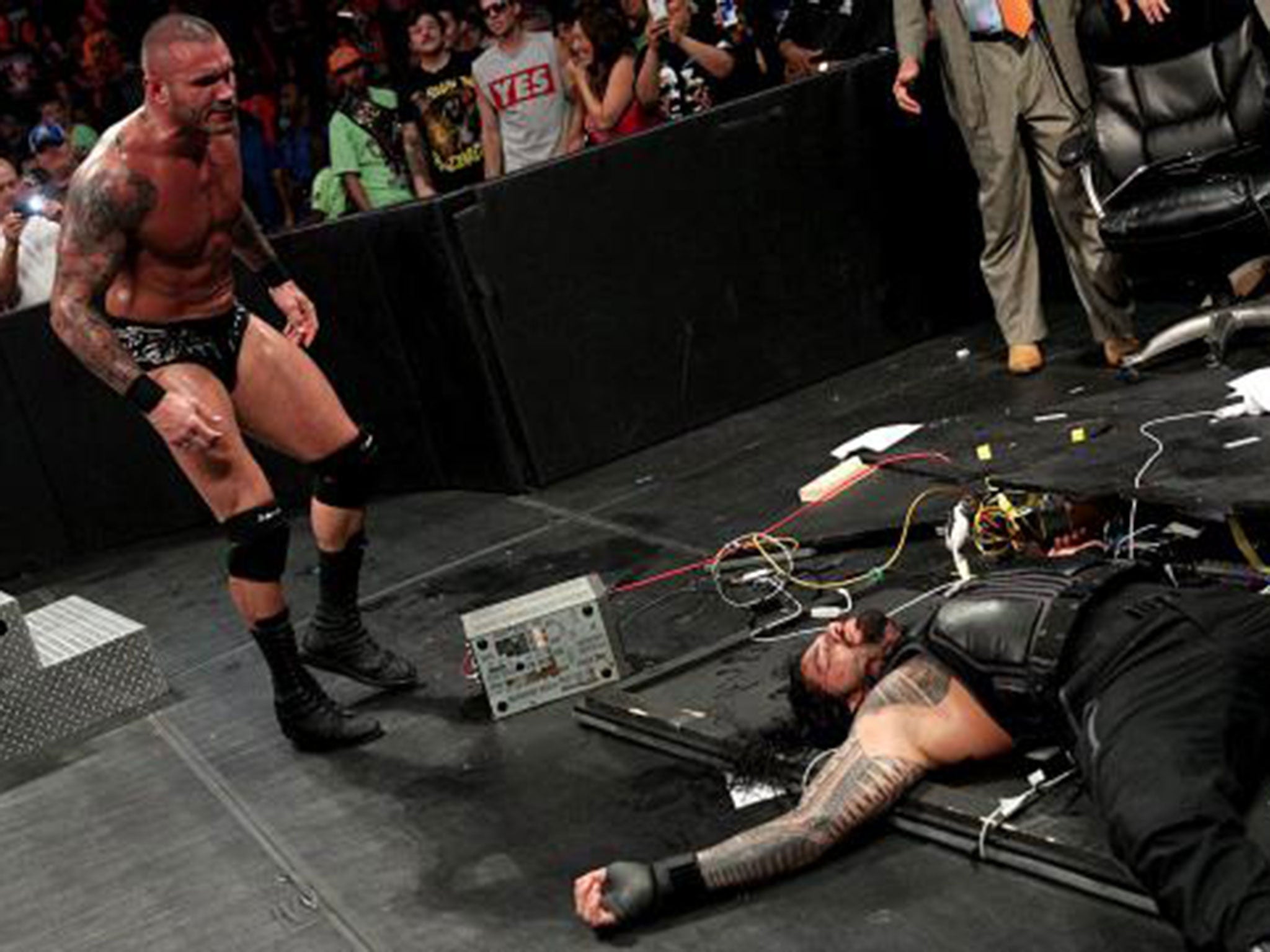 Orton stands over the prone body of Reigns after putting him through the announcers table