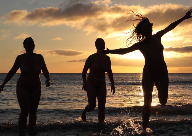 <p>Nudists take part in the annual North East Skinny Dip as the sun rises at Druridge Bay in Northumberland</p>